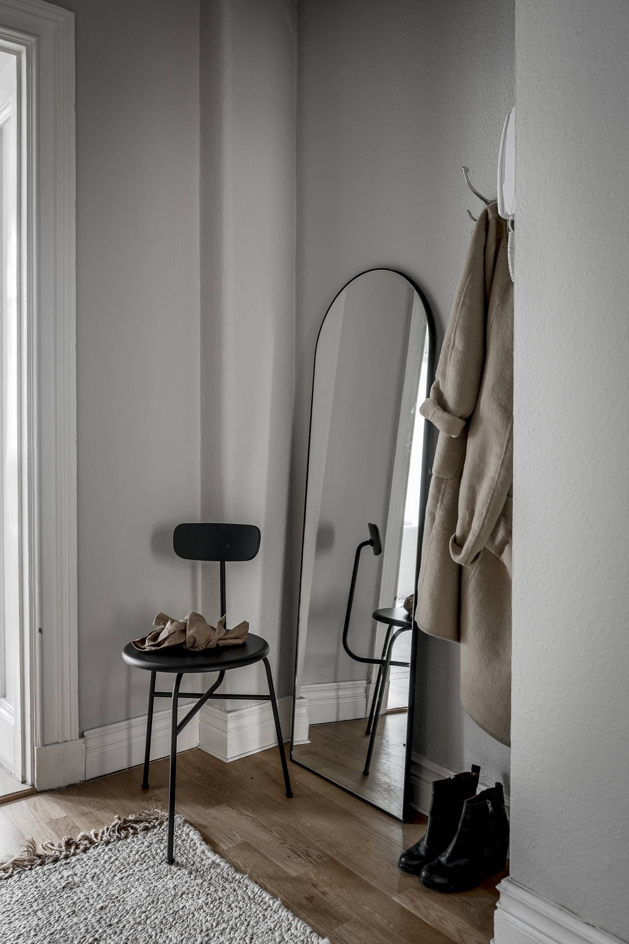 Recibidor pequeño con silla negra y espejo de pie ovalado