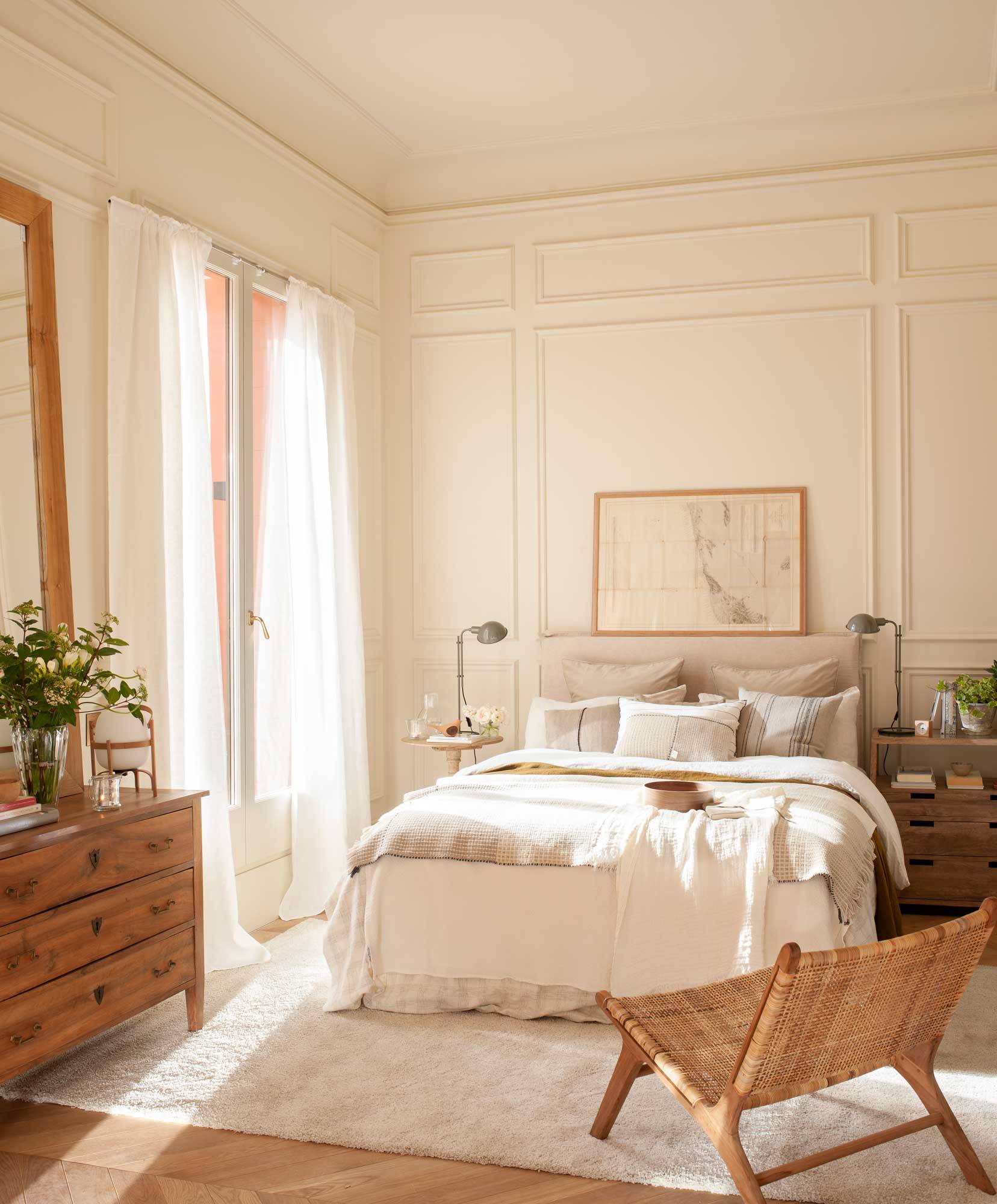 Dormitorio clásico en blanco con butaca de ratán y molduras decorativas en las paredes 00501570 O