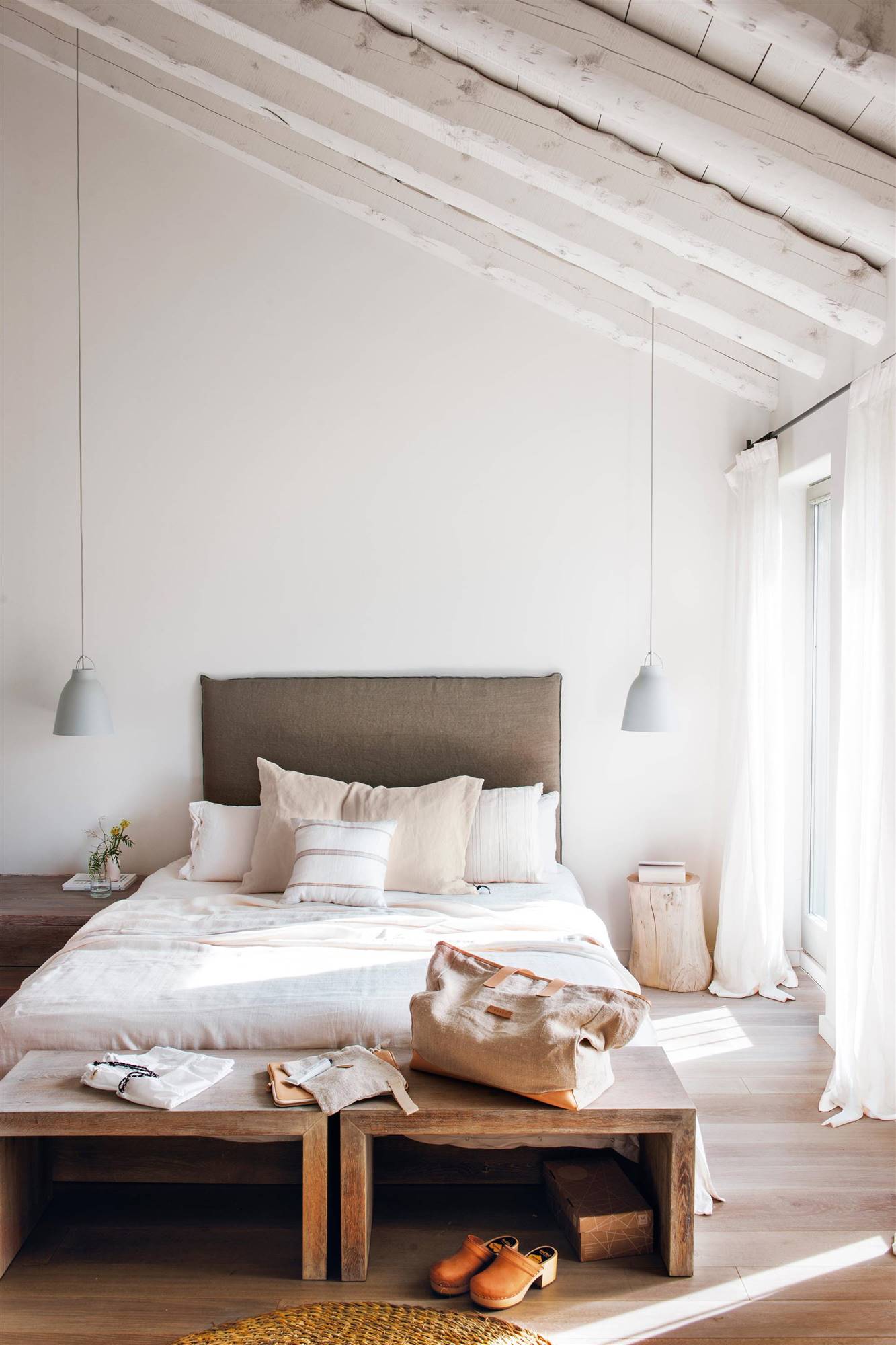 Dormitorio minimalista en blanco con cabecero tapizado.