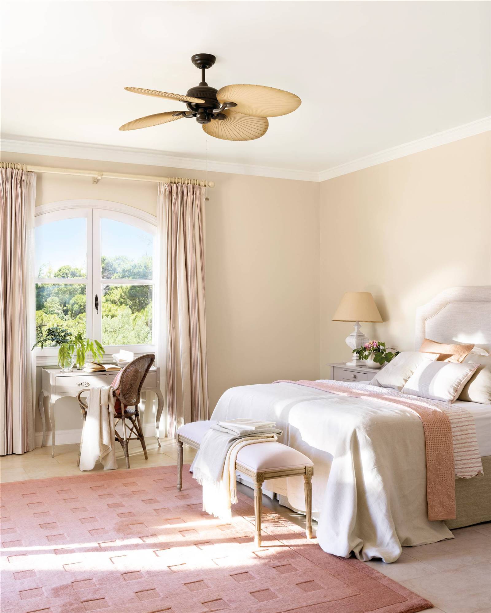 Dormitorio clásico con cabecero tapizado, alfombra salmón y ventilador de techo.