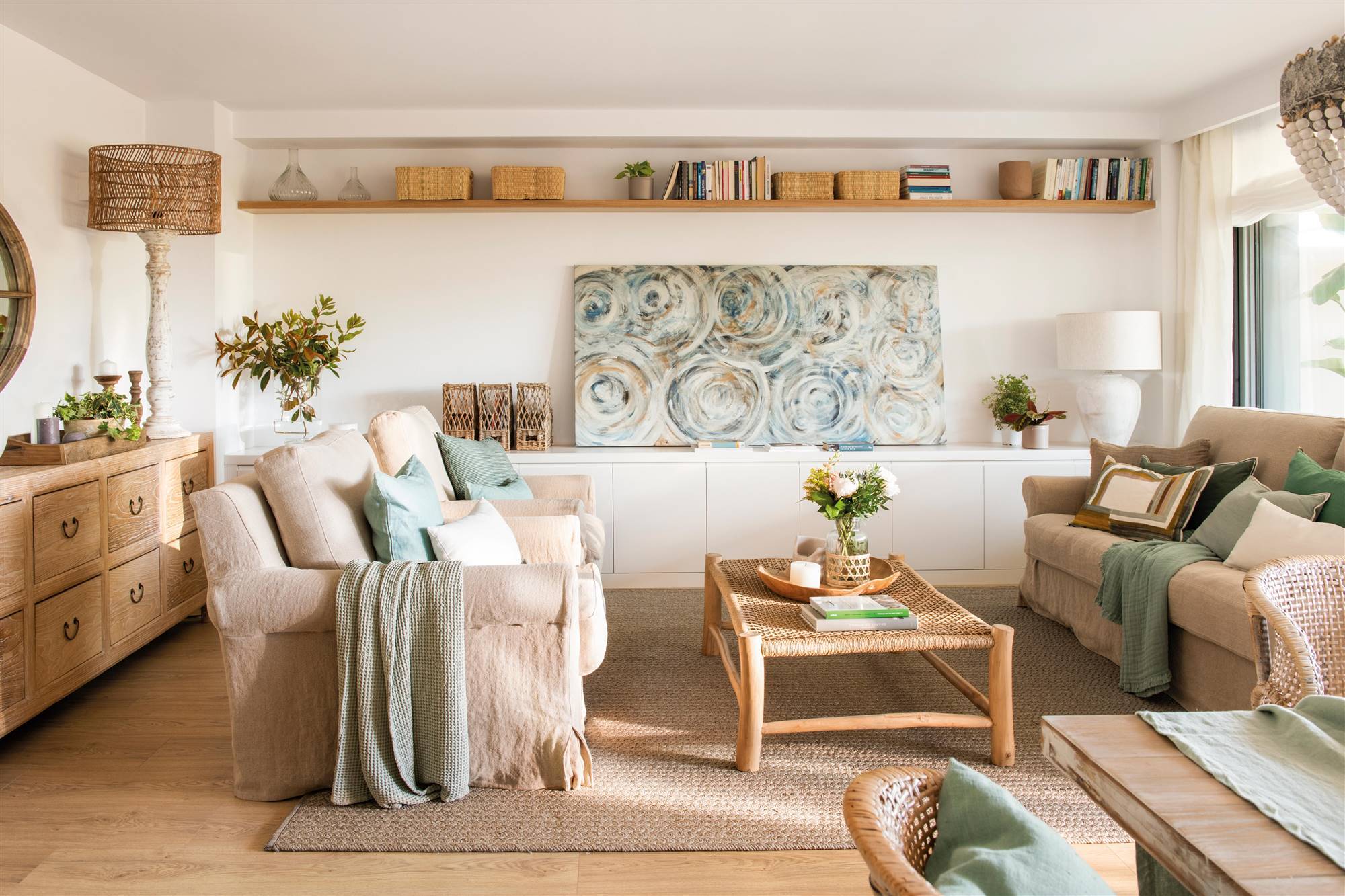 Salón con sofás claros con funda de lino, cuadro abstracto y balda de madera. 