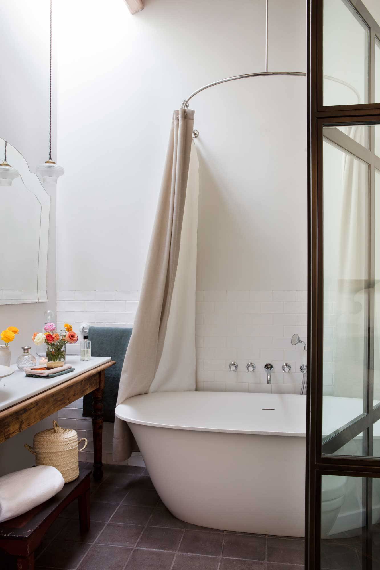 Baño con bañera exenta y mueble bajolavabo de anticuario. 