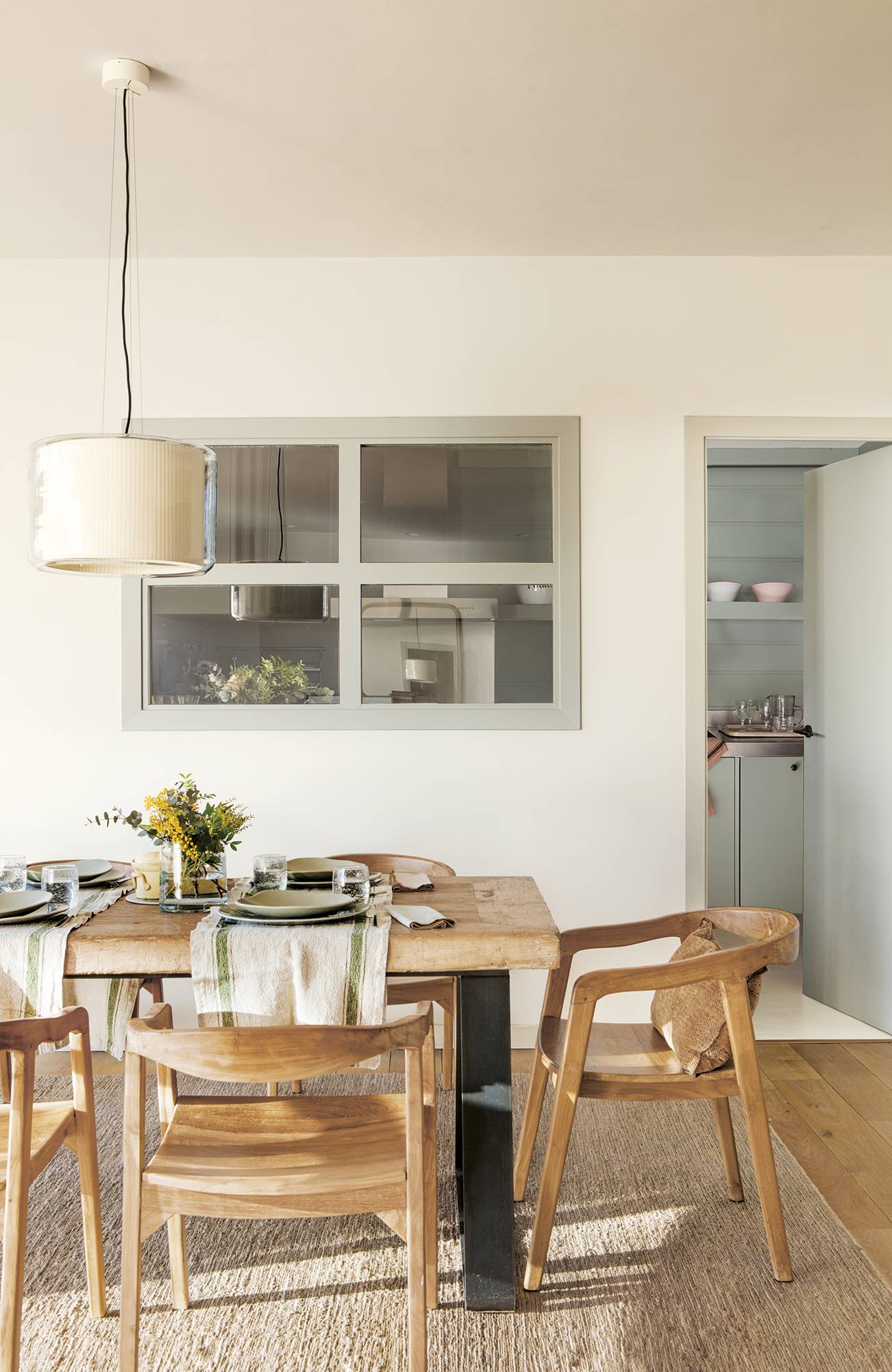Comedor de estilo rústico industrial comunicado con la cocina a través de una ventana en la pared.