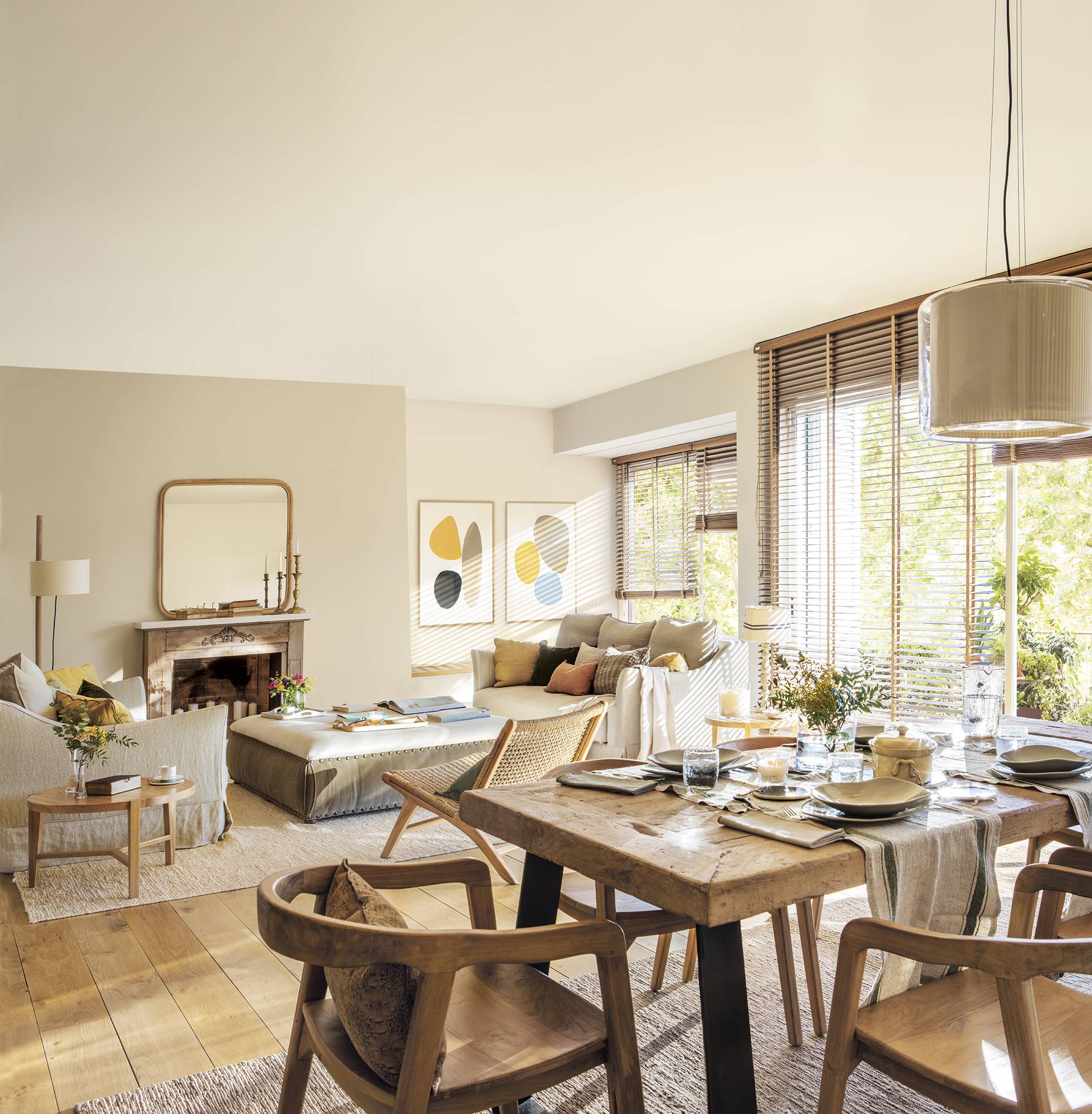 Comedor abierto al salón con mesa y sillas de madera y lámparas de techo modernas.