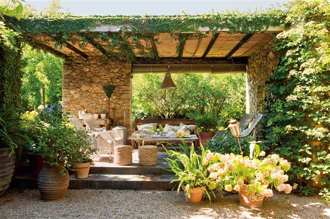 Pérgola con techo de cañizo y paredes de piedra en jardín