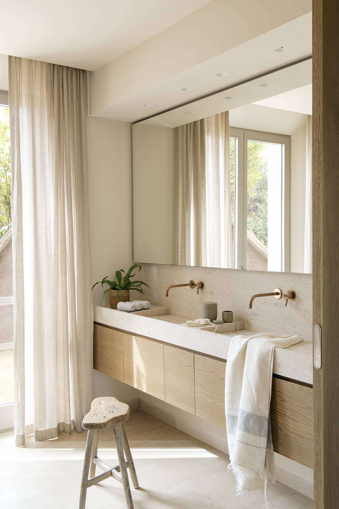 Baño con mueble flotante, maxi espejo y banco de madera rústico.