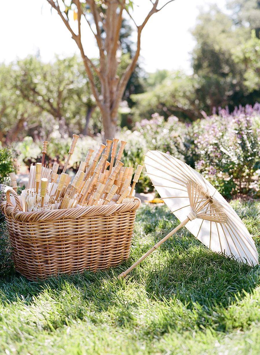 Decoracion de boda con cestas de mimbre para poner sombrillas.