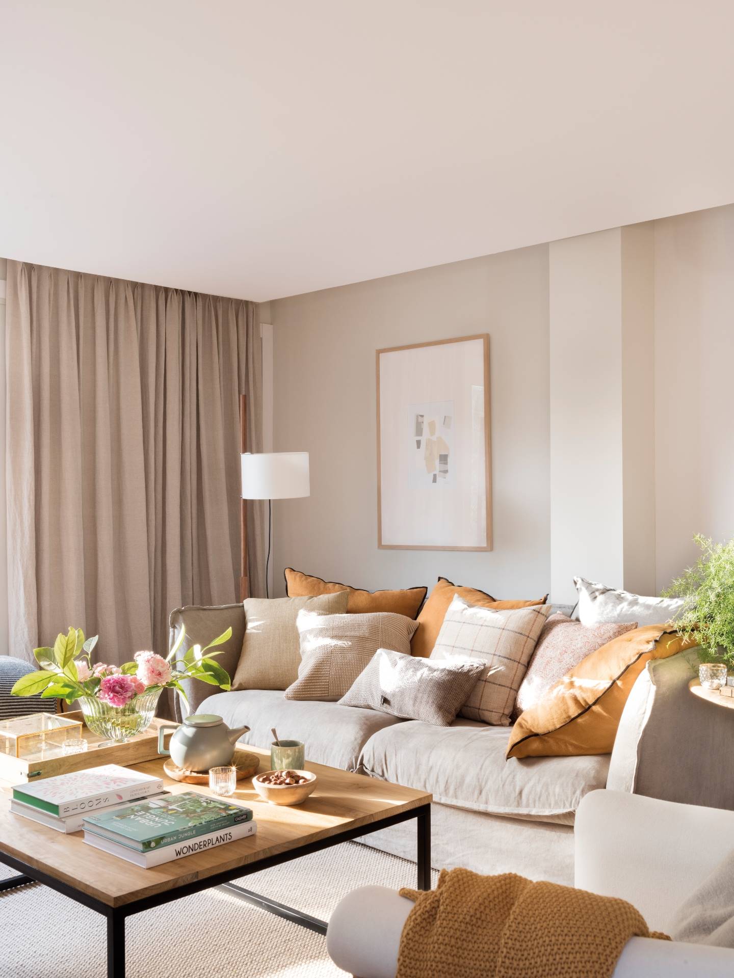 Salón pequeño con sofá de lino beige y cojines ocres y blancos. 
