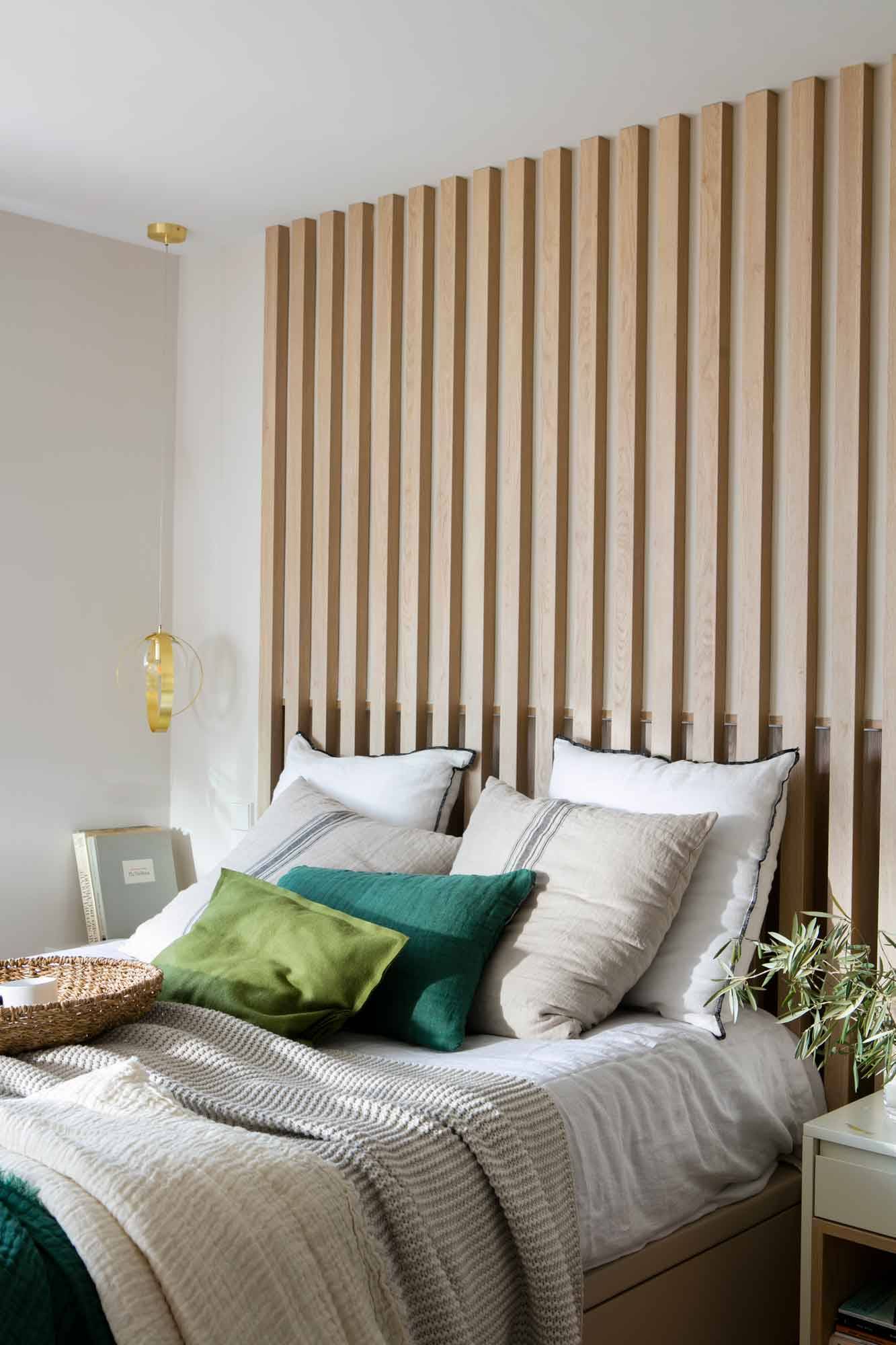 Dormitorio con cabecero de listones de madera.