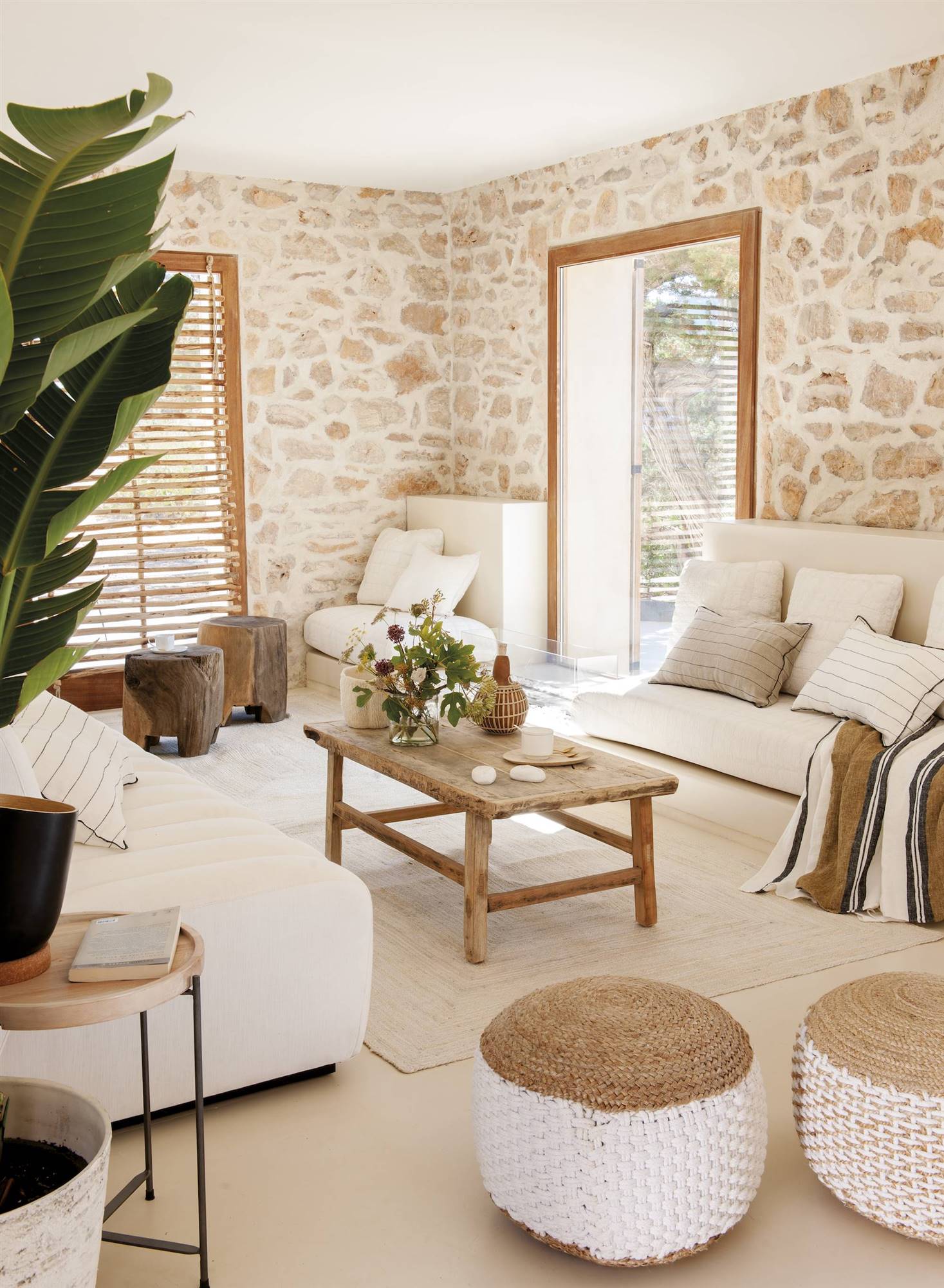 Salón son sofás blancos, mesa de madera y pufs de fibra. 