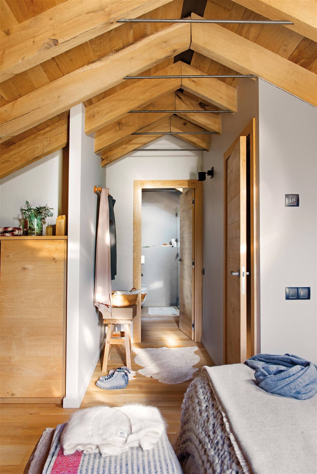 Dormitorio abuhardillado con vestidor en pasillo y baño en suite con puertas de madera