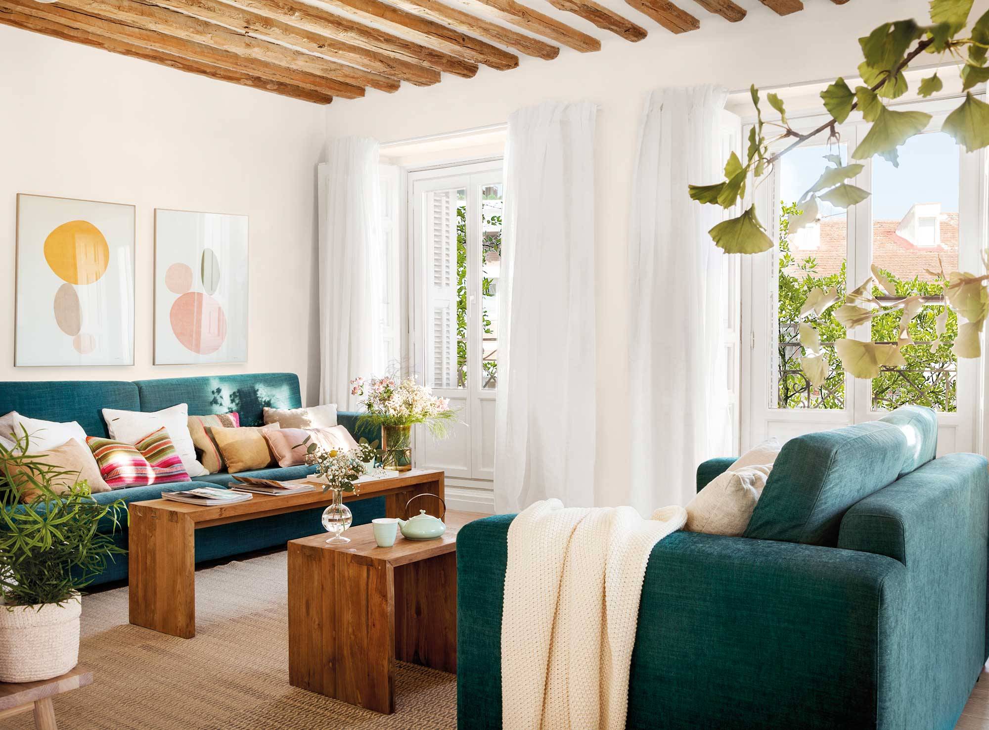 Salón con dos sofás verdes y dos mesas de centro de madera. 