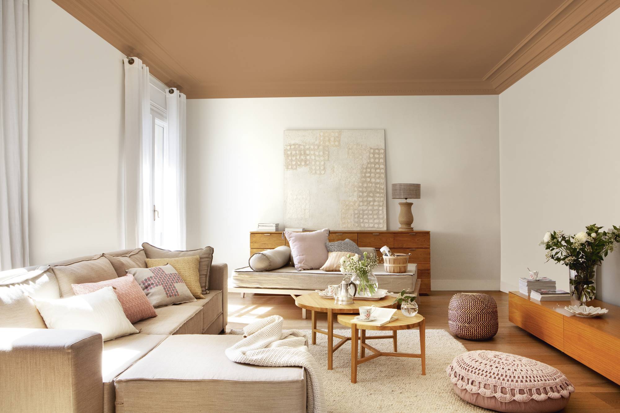 Salón con paredes blancas y techo marrón y sofá con chaise longue. 