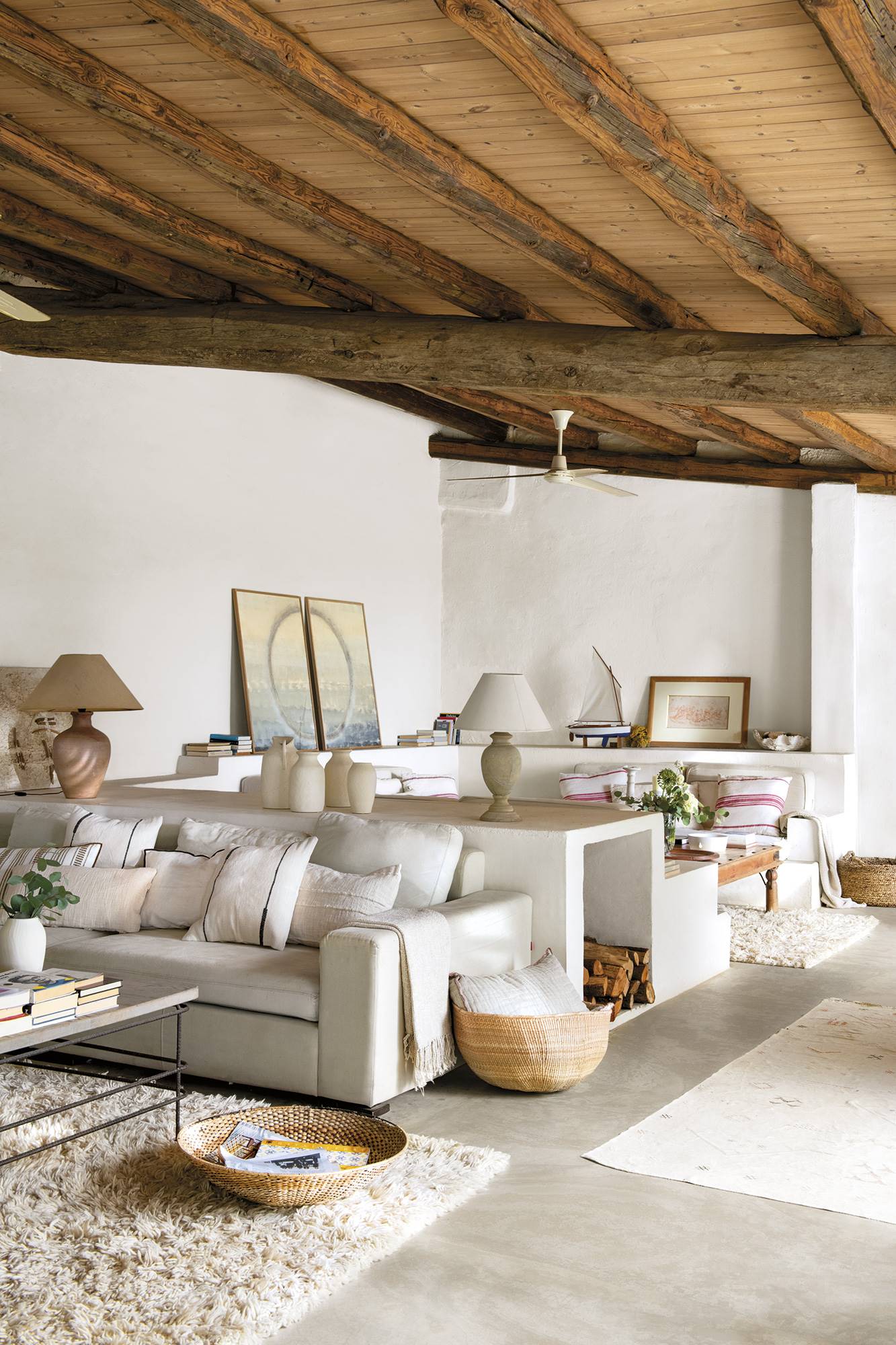 Salón mediterráneo blanco con muebles de obra y vigas en el techo.