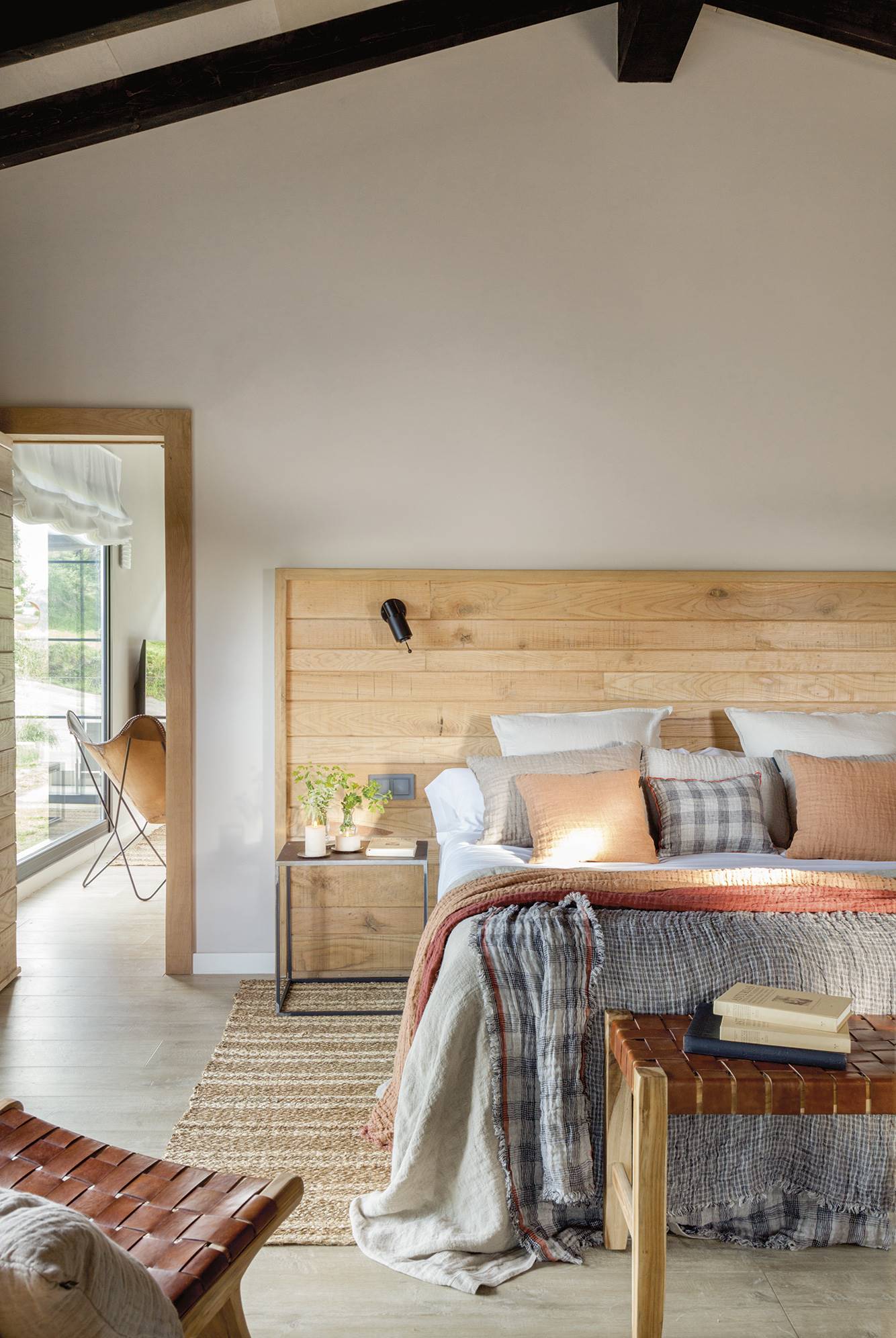 Dormitorio en una cabaña de montaña, de estilo industrial con cabecero de madera y plaid a cuadros.