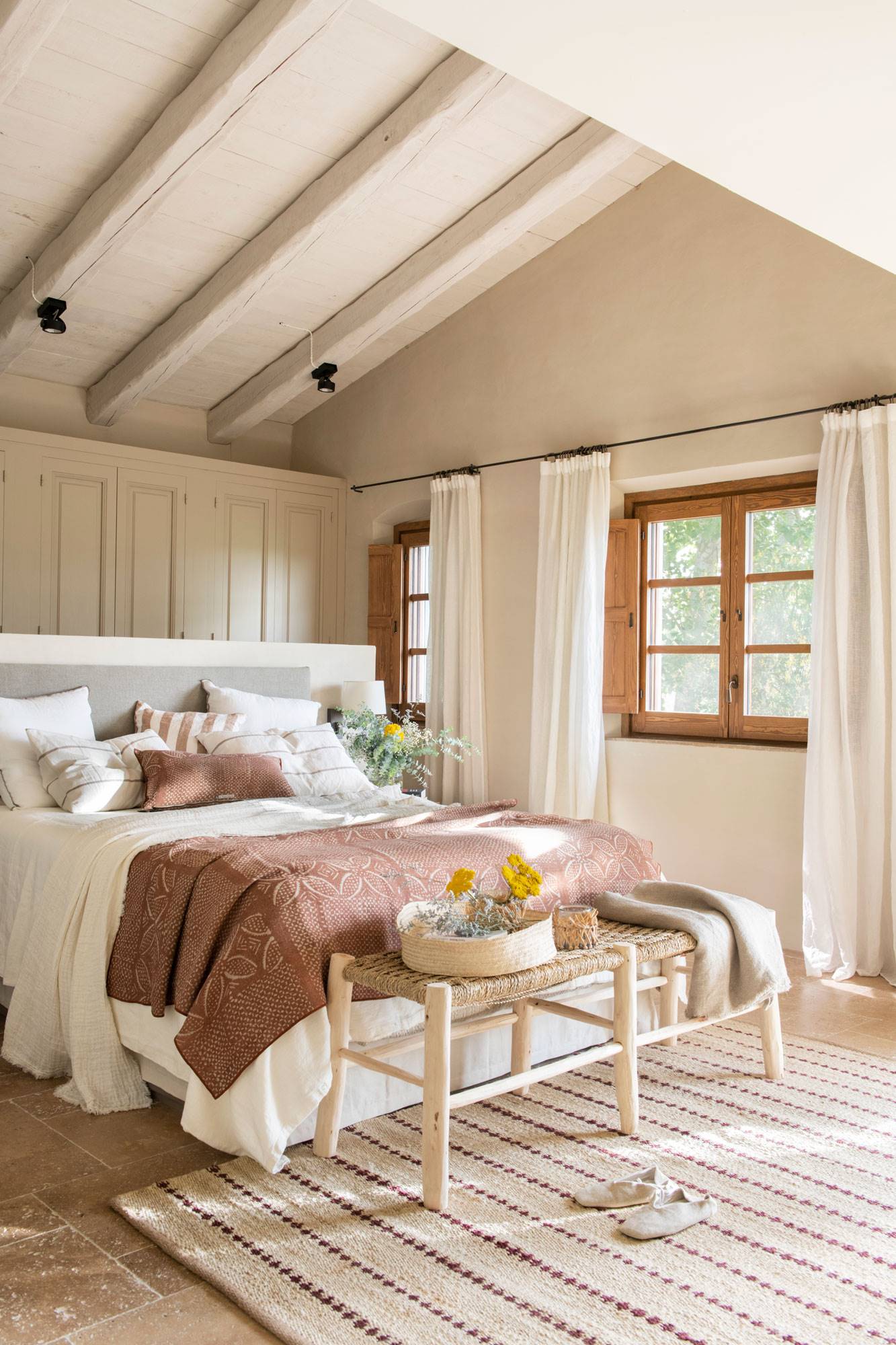 Dormitorio abuhardillado con el techo pintado de blanco.