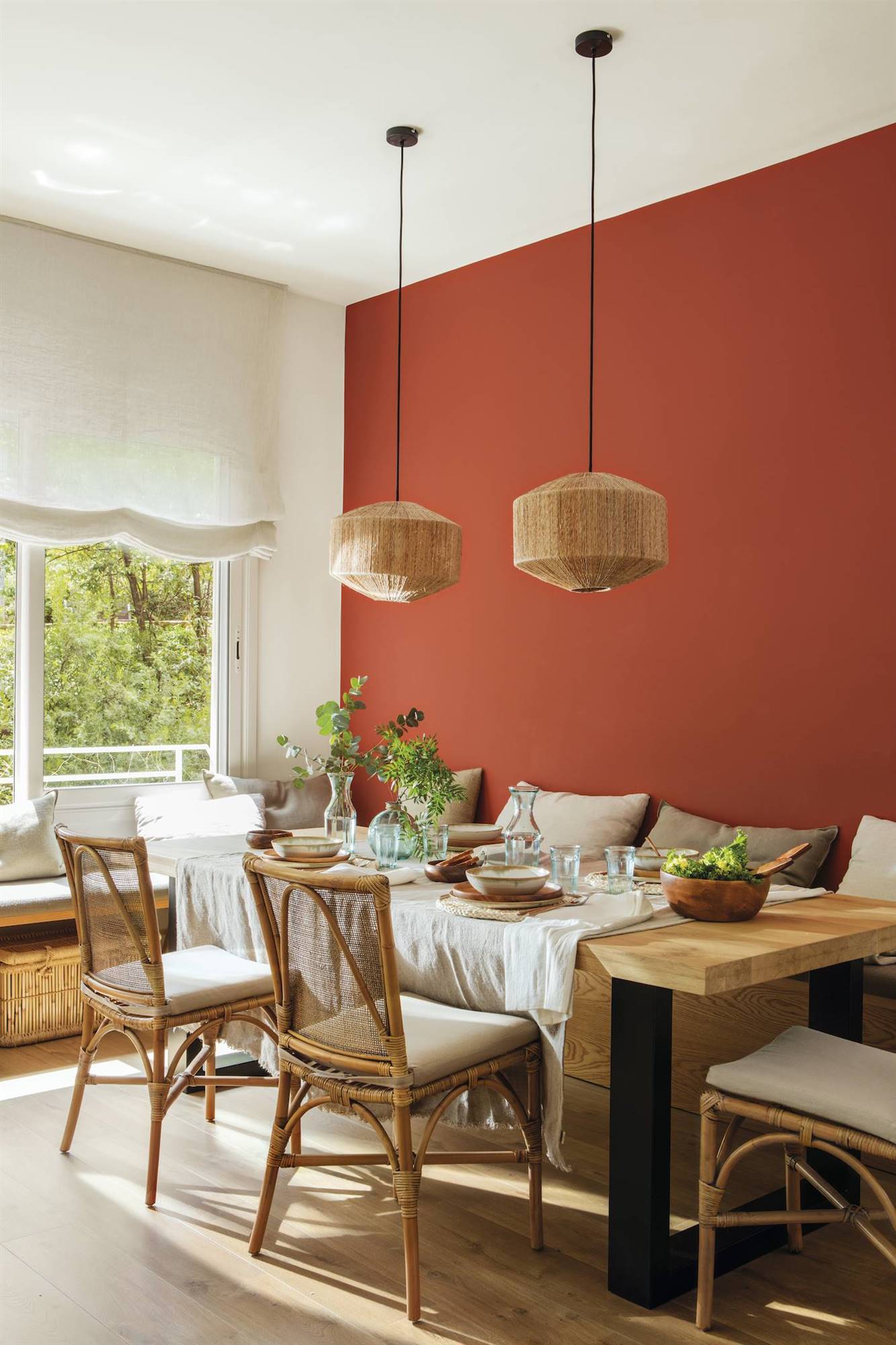 Comedor con pared frontal en tonos rojos y una gran mesa realizada a medida en madera y hierro