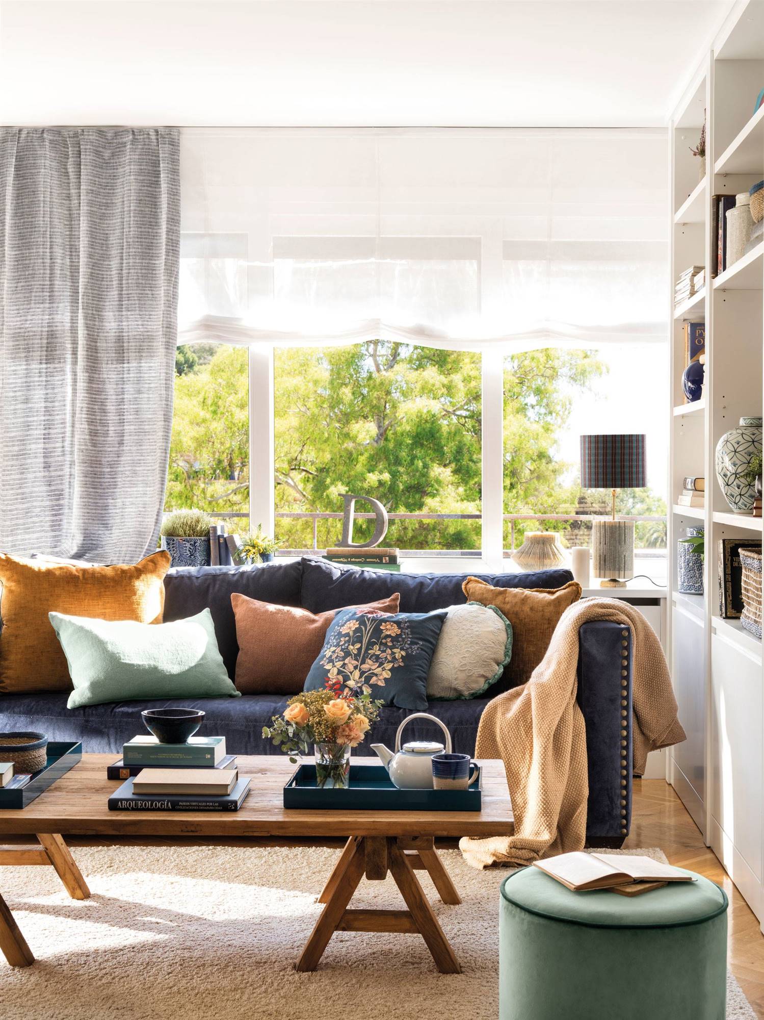 Salón con sofá azul y textiles en color marrón. 
