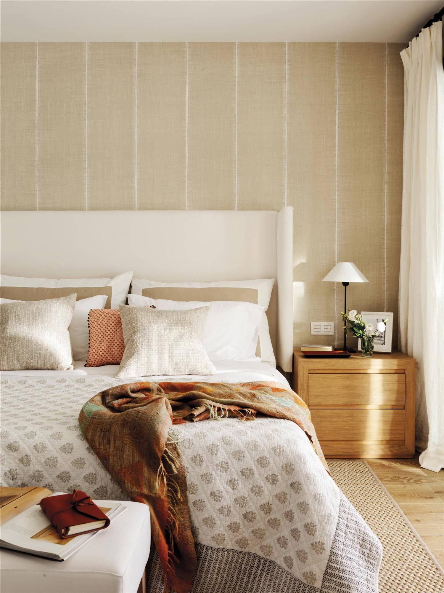Un dormitorio principal con cabecero con orejas de Antima, papel pintado y plaid sobre la cama. 