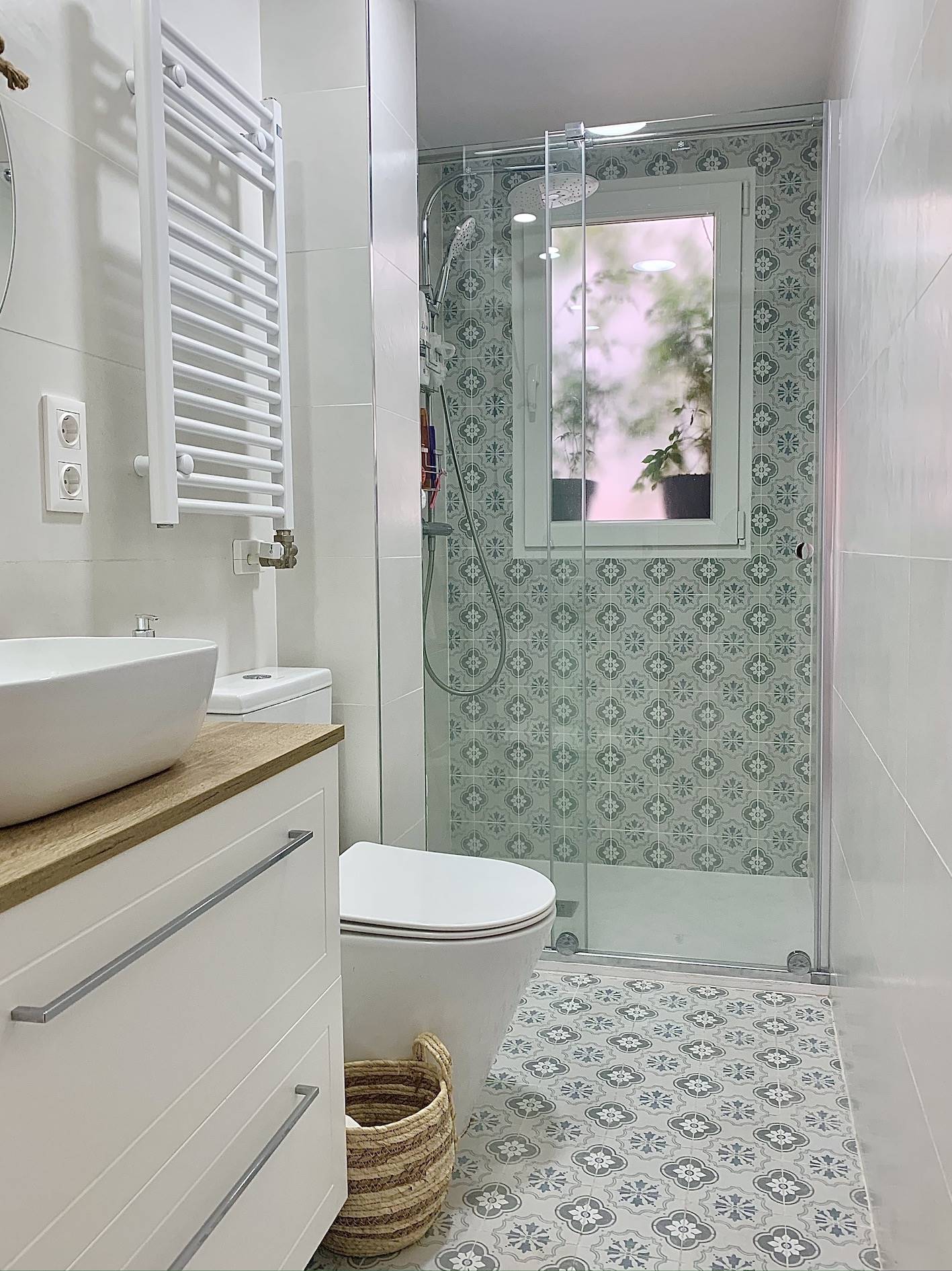 Un baño súper estiloso en tonos blancos con ducha con mampara de cristal tras la reforma.