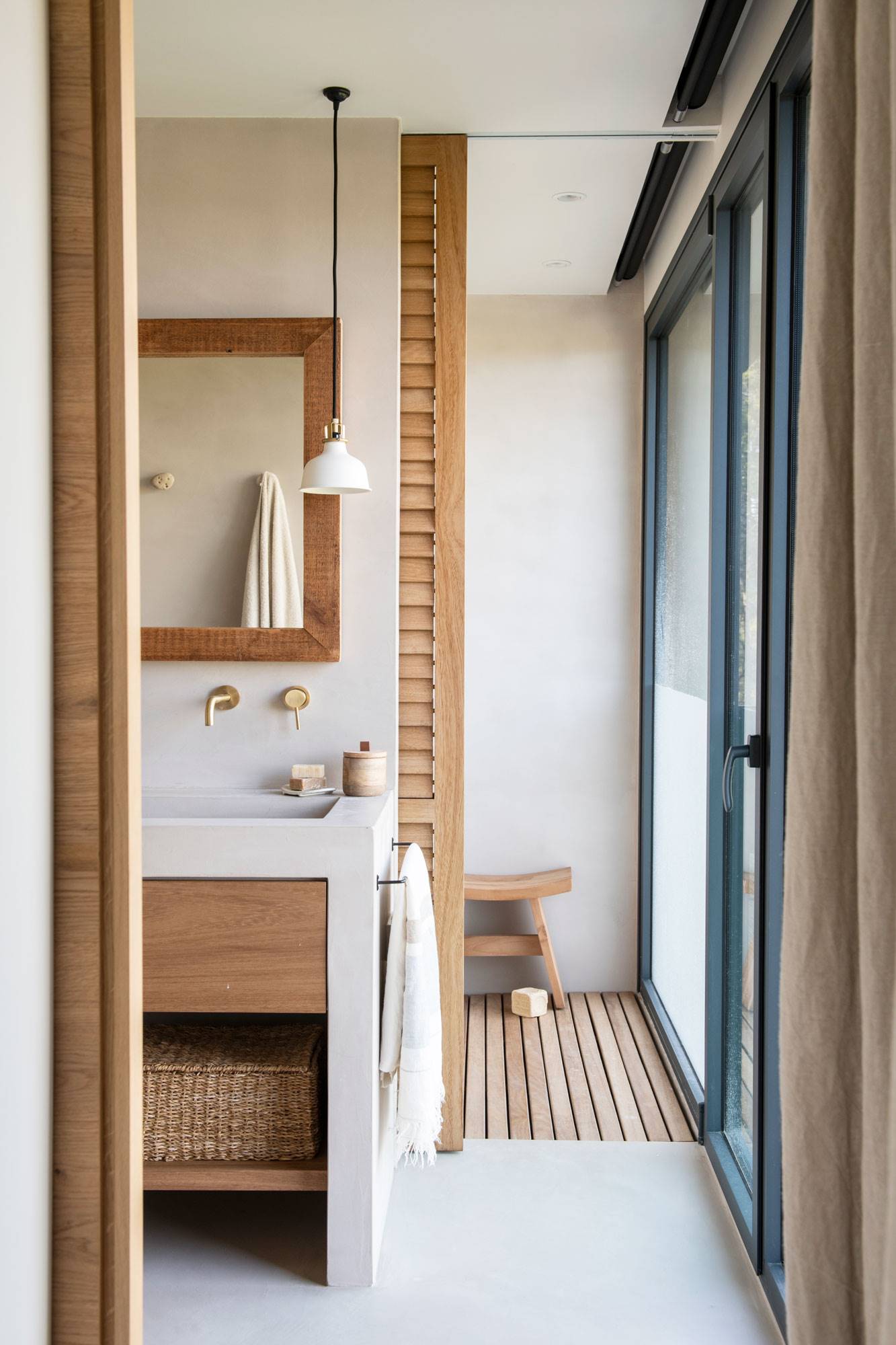 Baño con ducha separados por una puerta corredera de lamas de madera. 