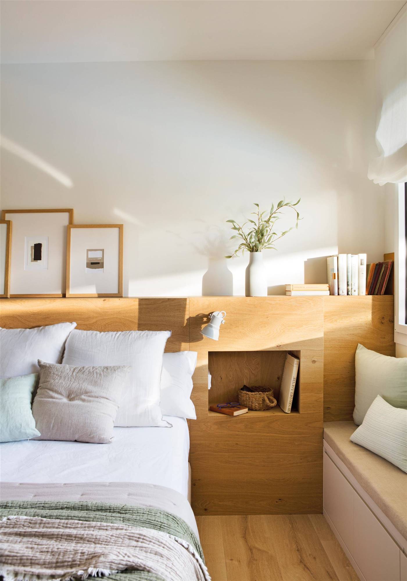 Dormitorio con cabecero de madera y mesillas integradas.