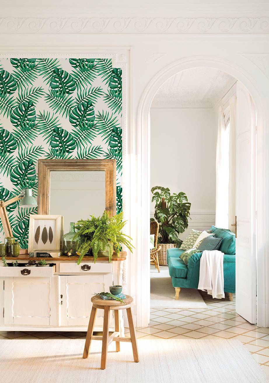 Aparador de madera blanca y pared decorada con un papel pintado tropical. 