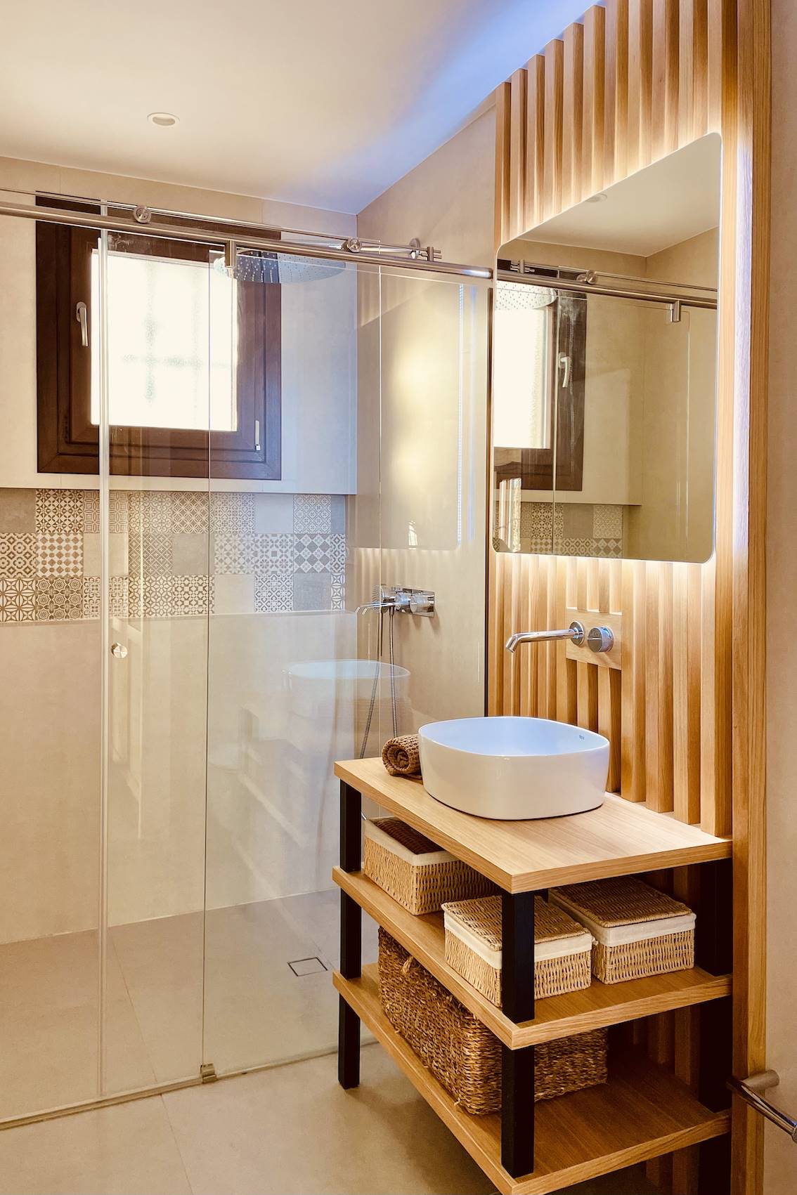 Baño con madera y hierro en el mueble del lavamanos y una amplia ducha con mampara de cristal.