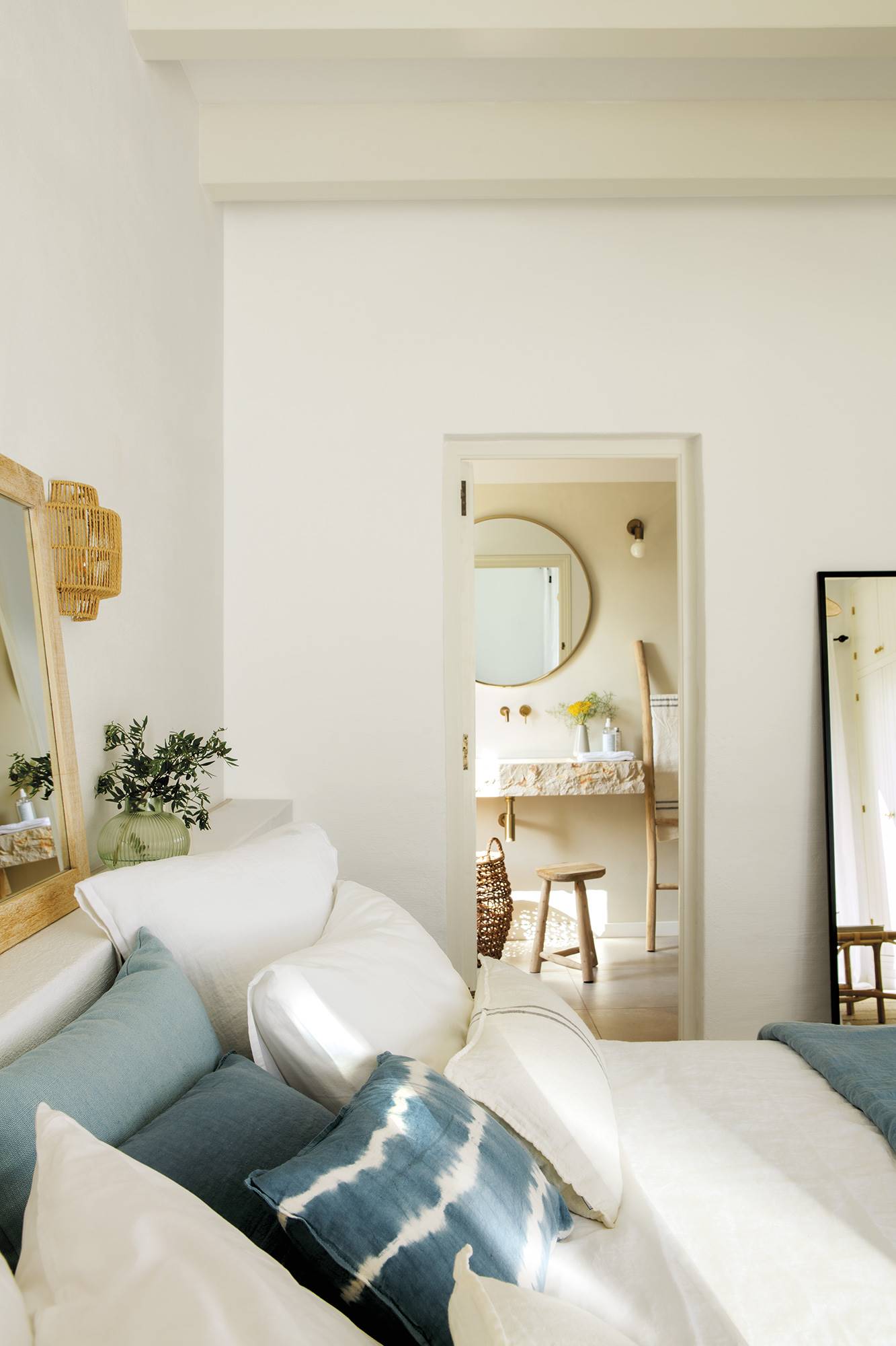 Dormitorio de estilo mediterráneo con cojines azules y ropa de cama blanca