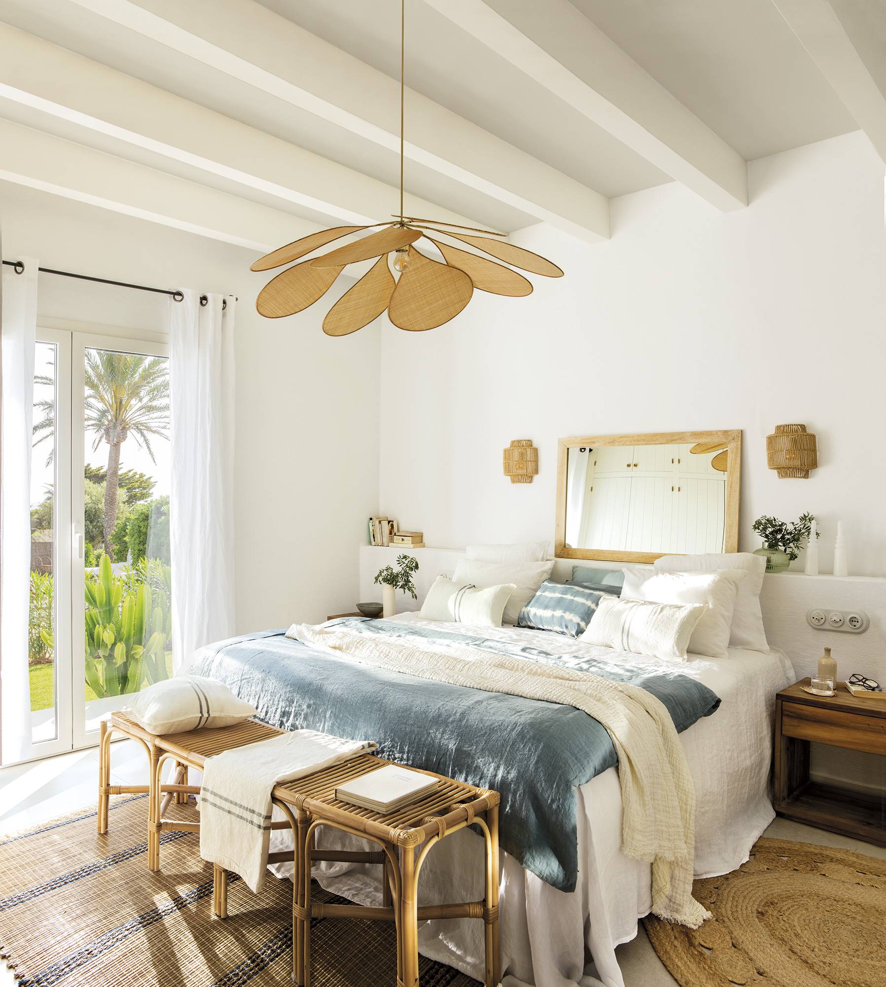 Dormitorio con cabecero de obra, cojines blancos y azules, lámpara de rafia y alfombras de fibras
