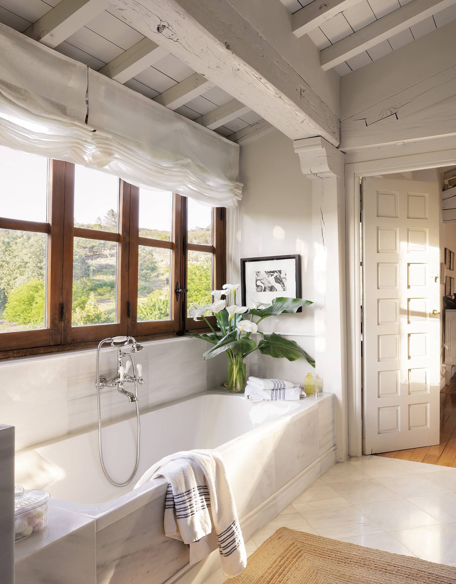 Baño con bañera acrílica bajo la ventana y suelos de mármol.