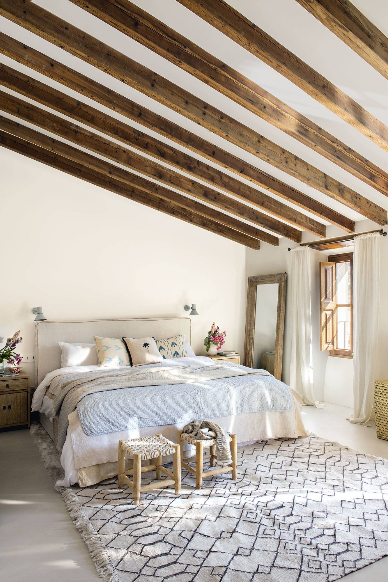 Dormitorio principal con el techo abuhardillado y las vigas de madera