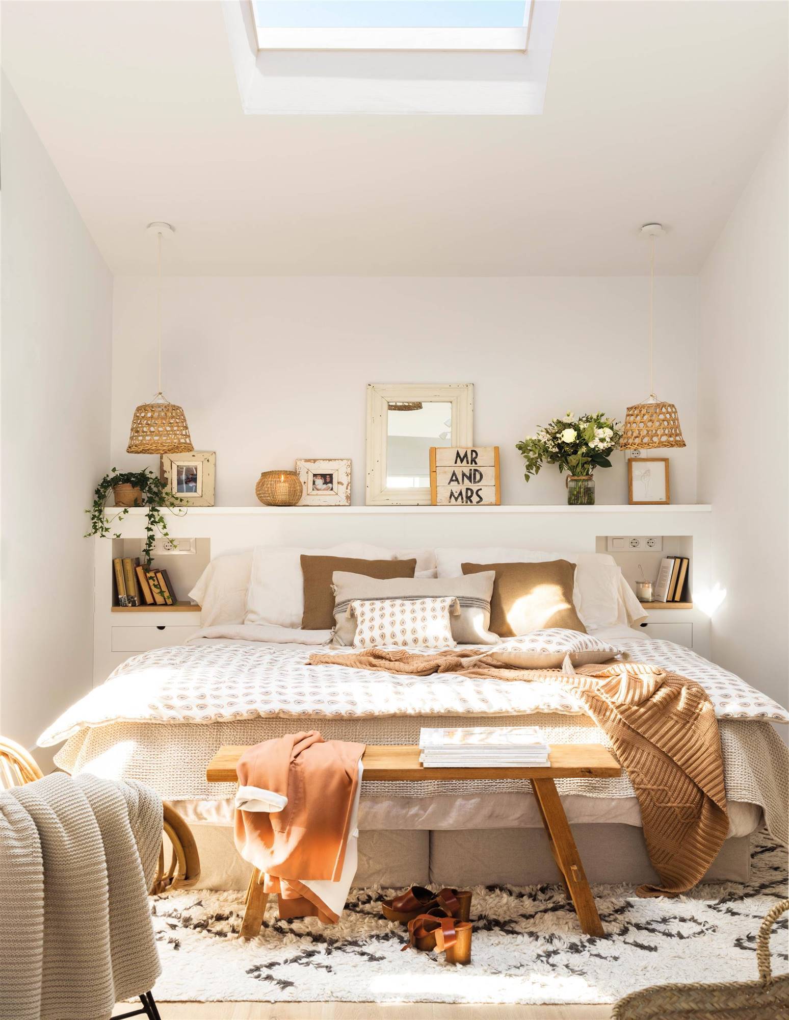 Dormitorio de estilo nórdico con cabecero blanco y banco de madera