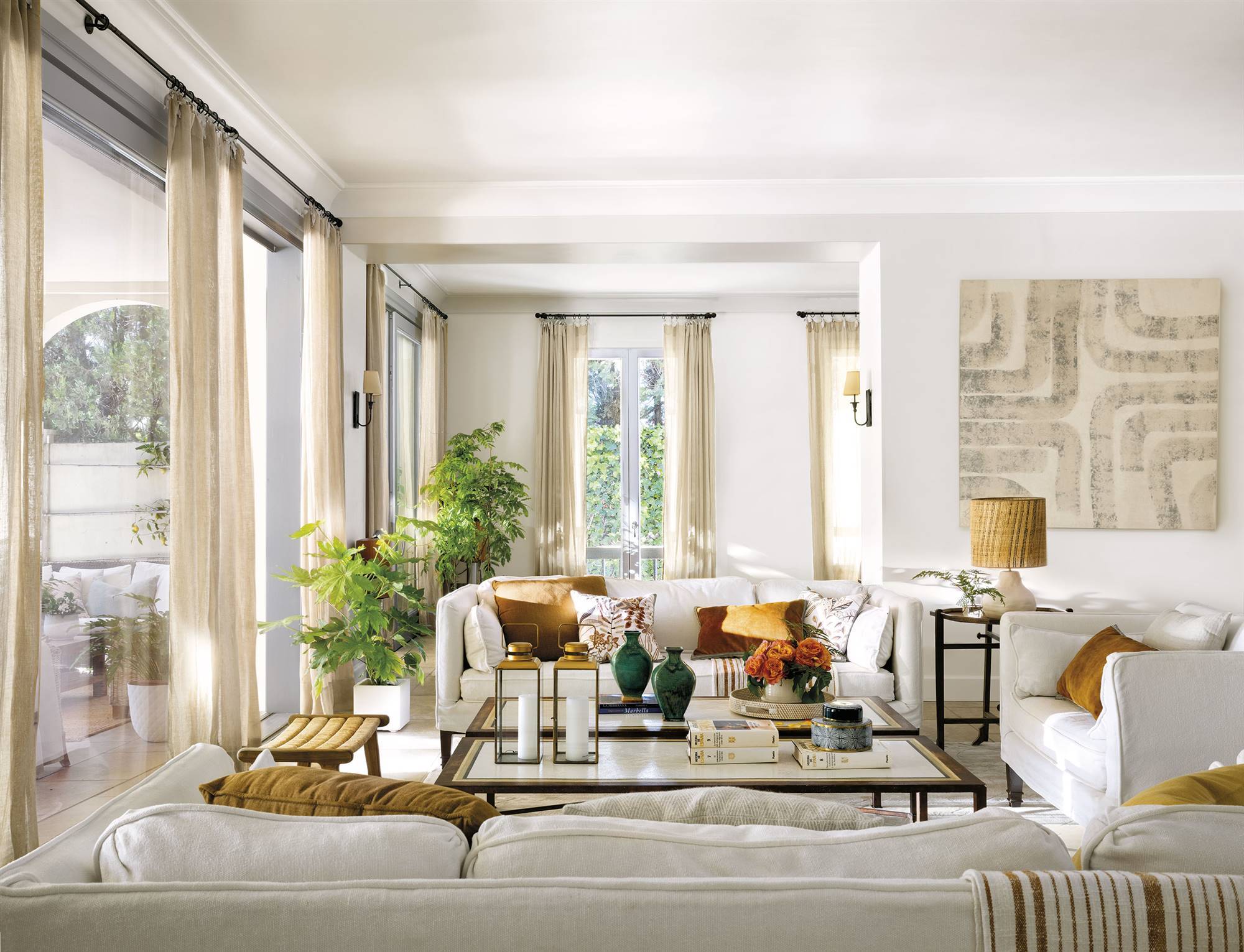 Salón clásico y atemporal en blanco con cojines mostaza y de terciopelo encima del sofá. 