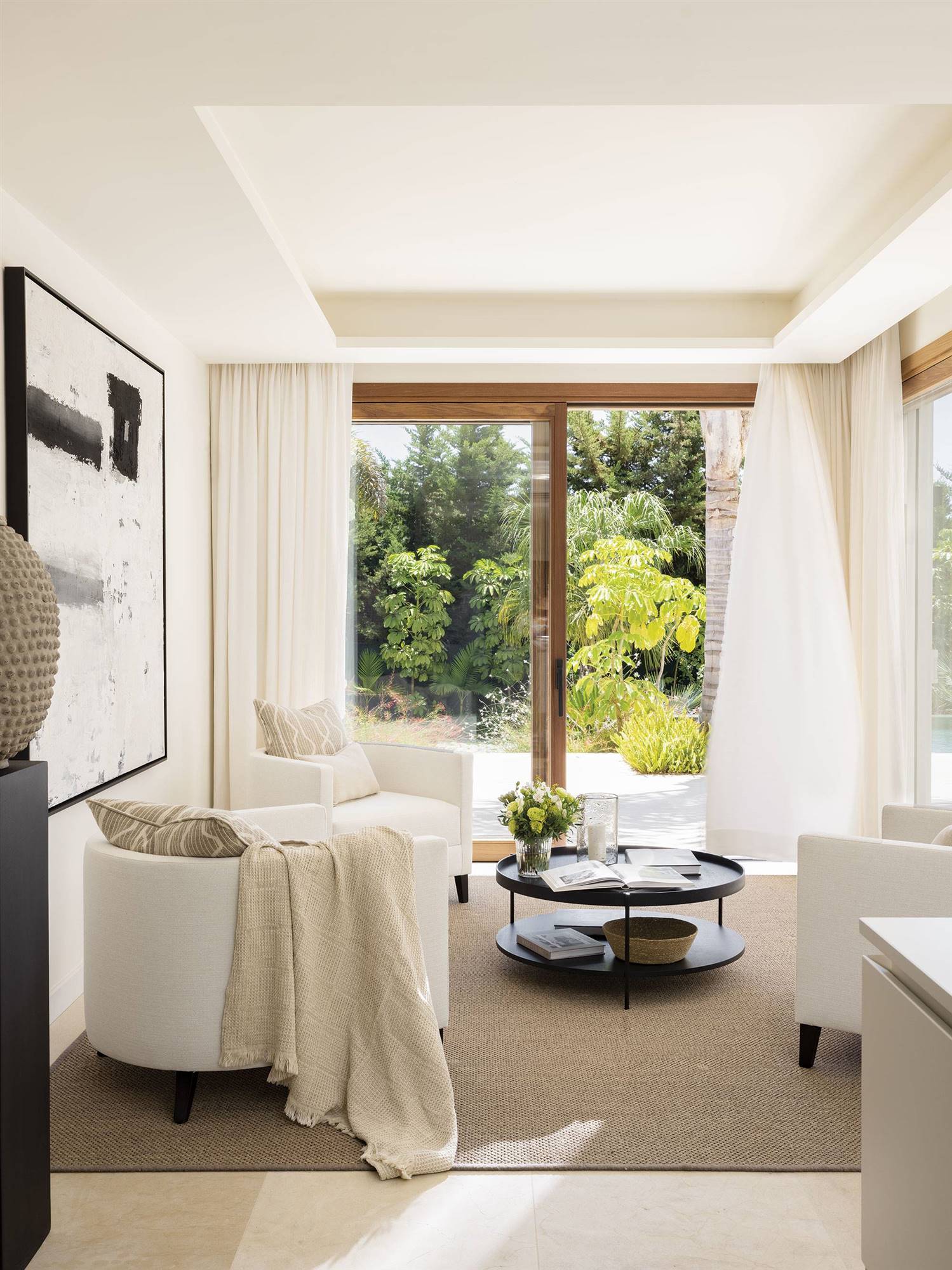 Rincón con butacas blancas, cortinas de lino ligero y alfombra.