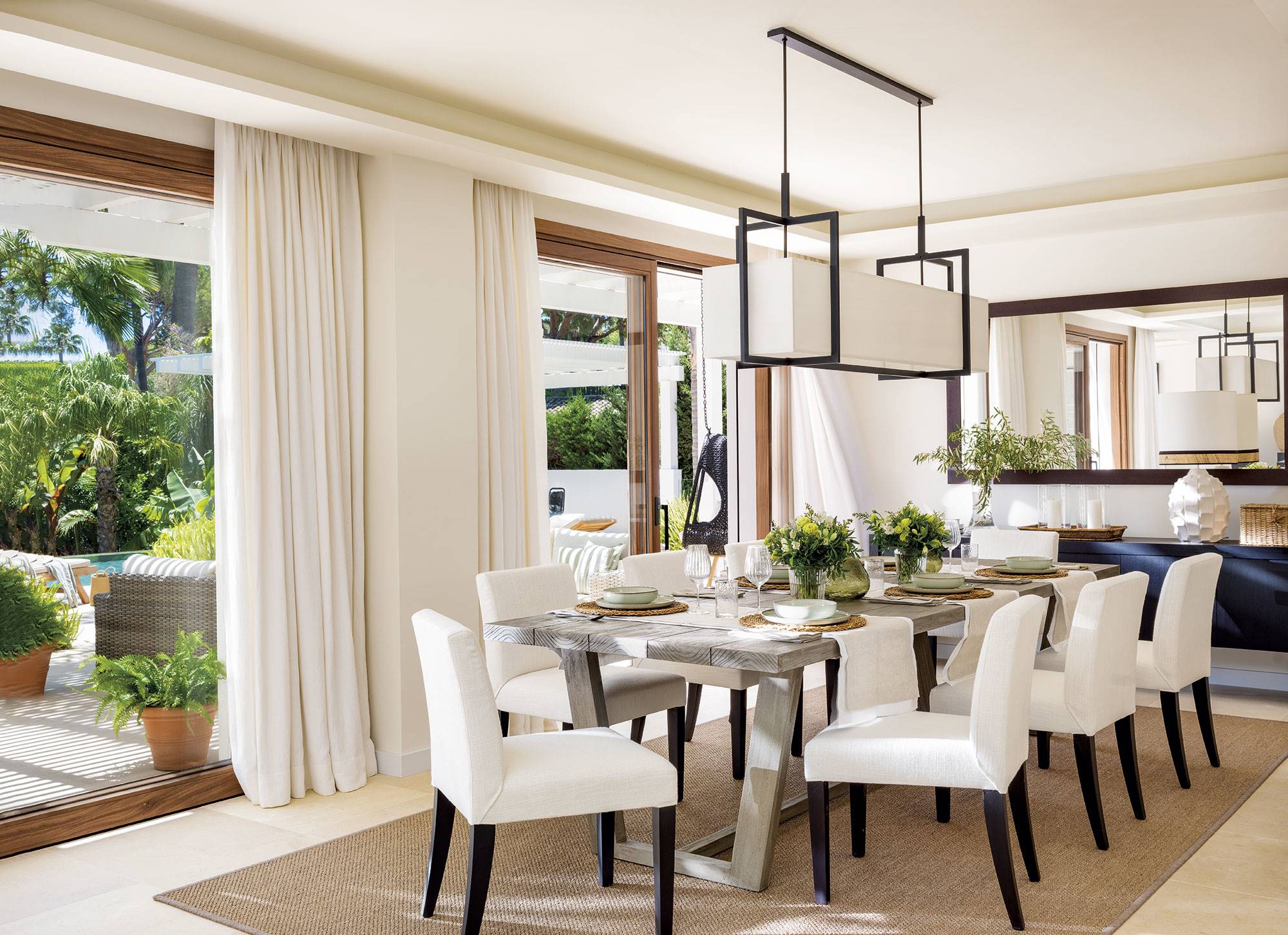 Comedor con sillas blancas, mesa de madera y lámpara de diseño. 