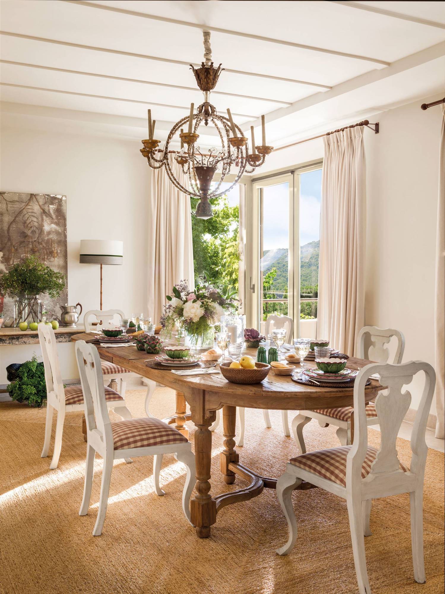 Comedor vintage con mesa ovalada de madera y sillas blancas. 