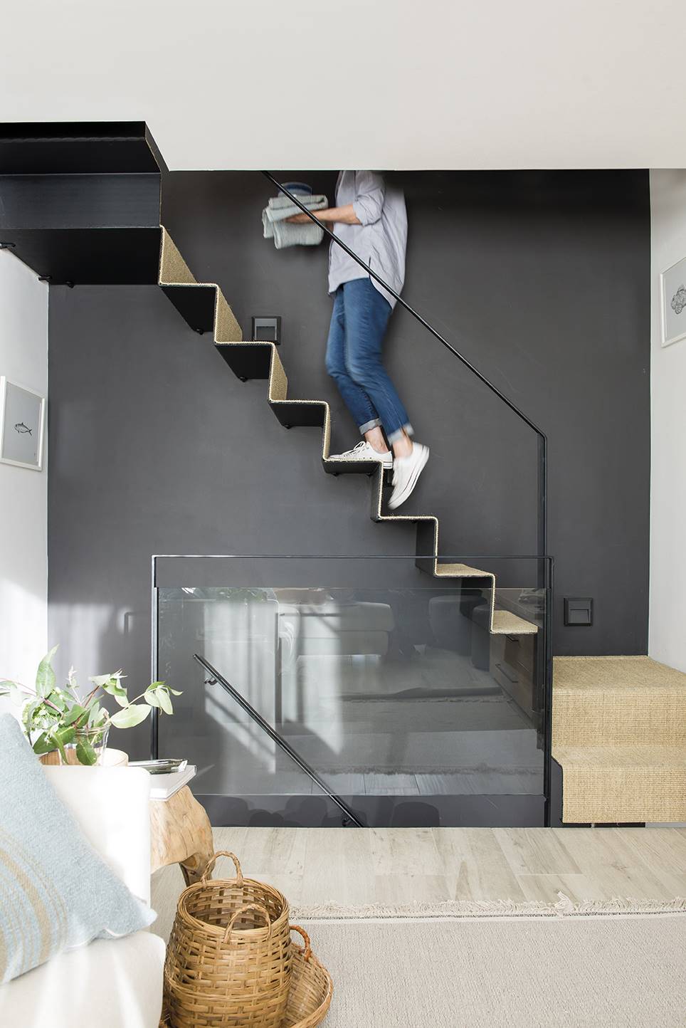 Mujer subiendo las escaleras de casa con pared de color gris carbón. 