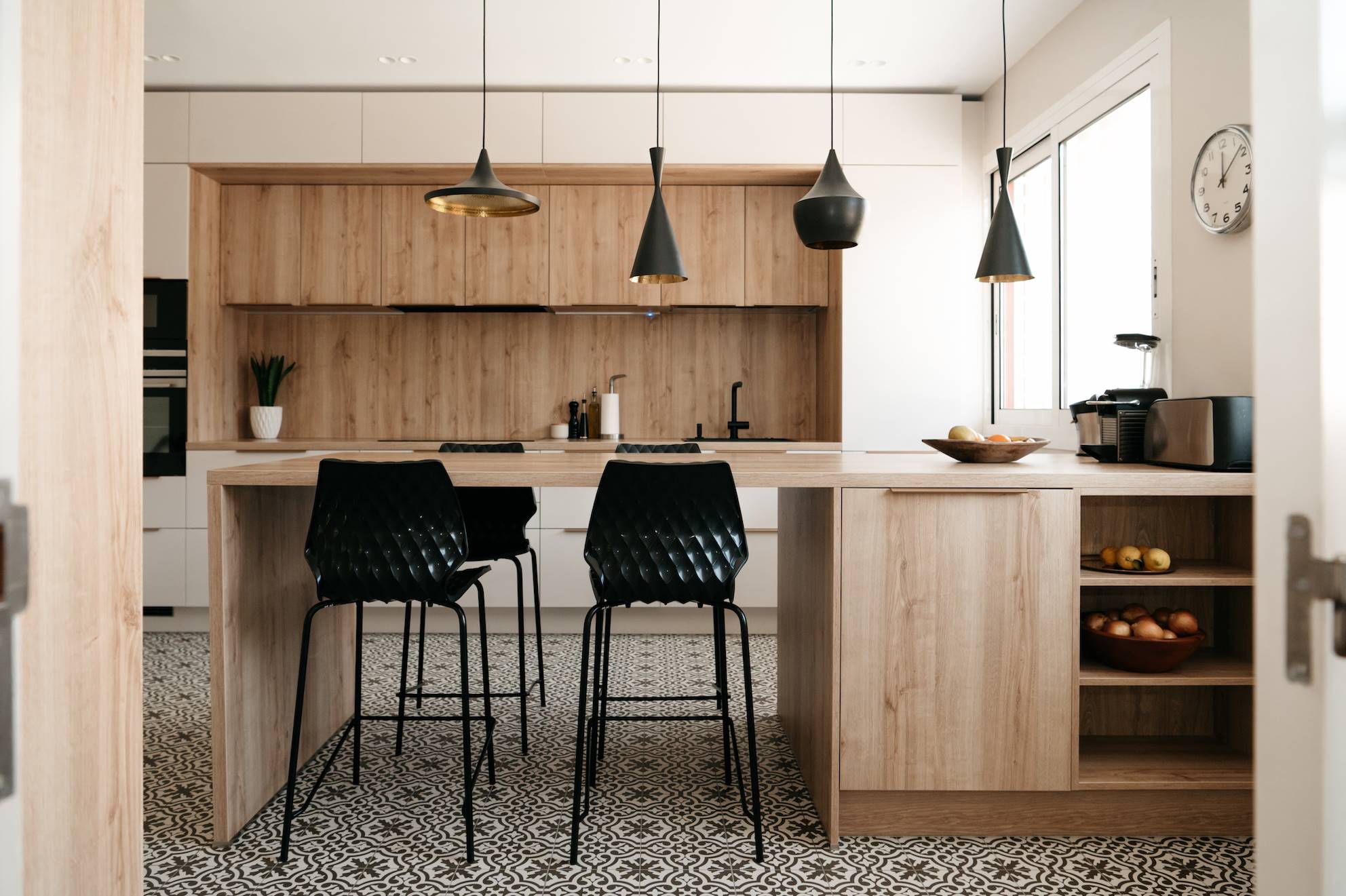 Una cocina moderna con isla y sillas altas en color negro.
