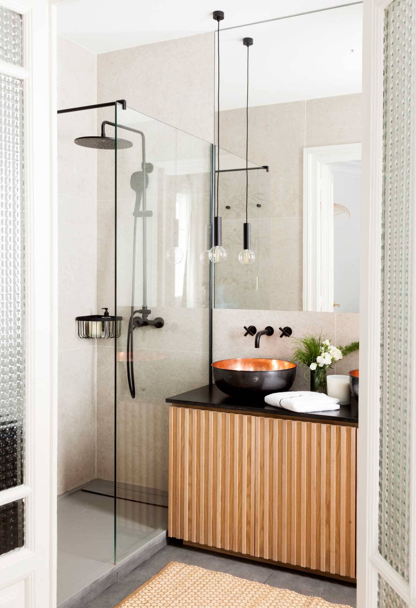 Baño pequeño y moderno con ducha, mampara y mueble de lavabo en negro y madera.