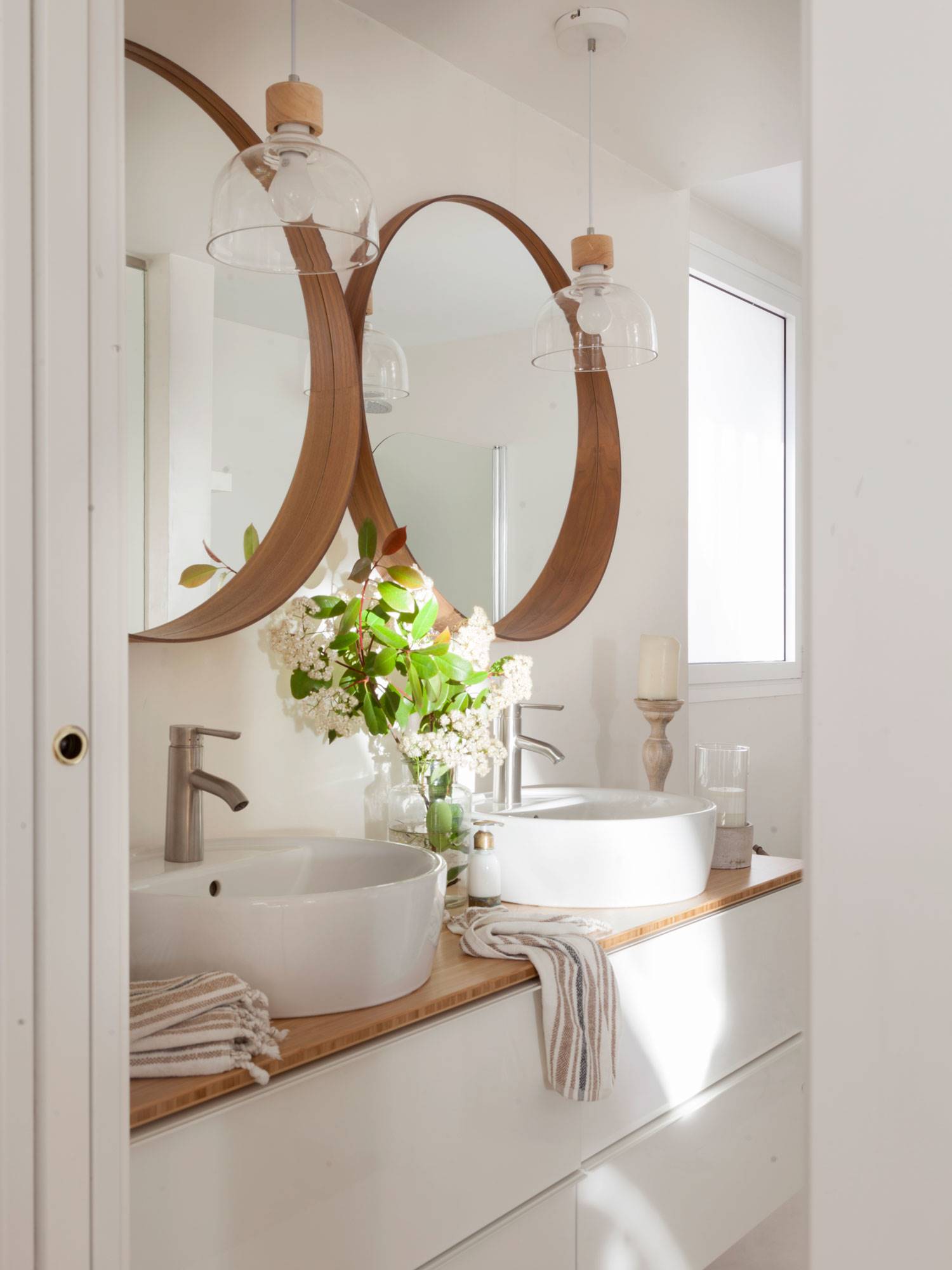 Baño con mueble de lavabo doble con espejos redondos de madera. 