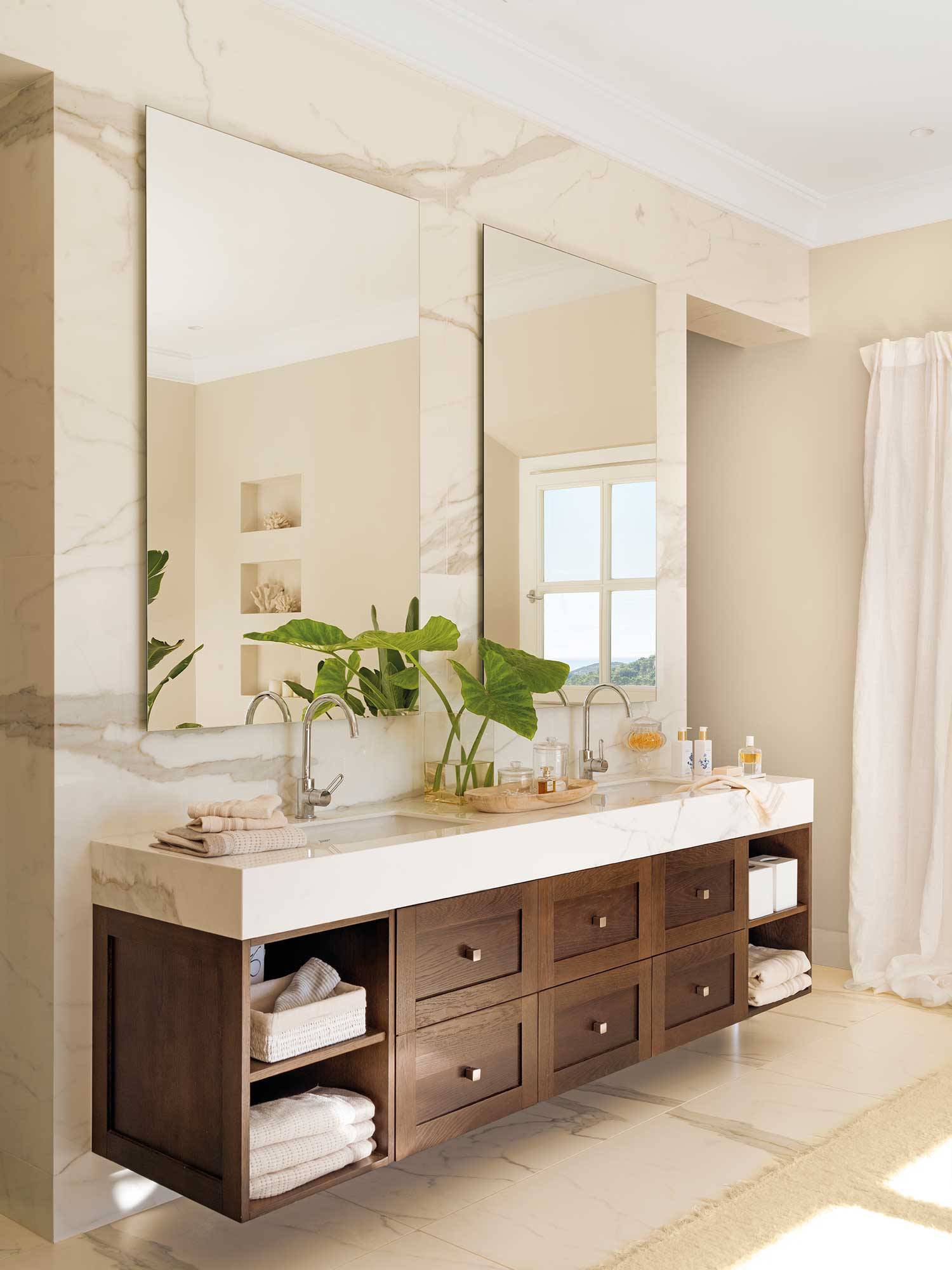 Baño con armario volado de madera con encimera y revestimientos de mármol. 