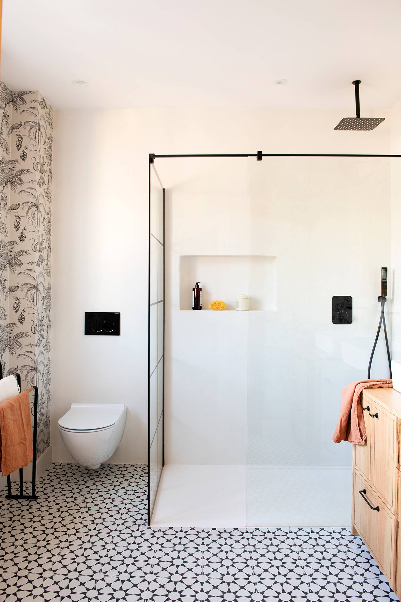 Baño con ducha grande con mampara negra y hornacina en la pared. 