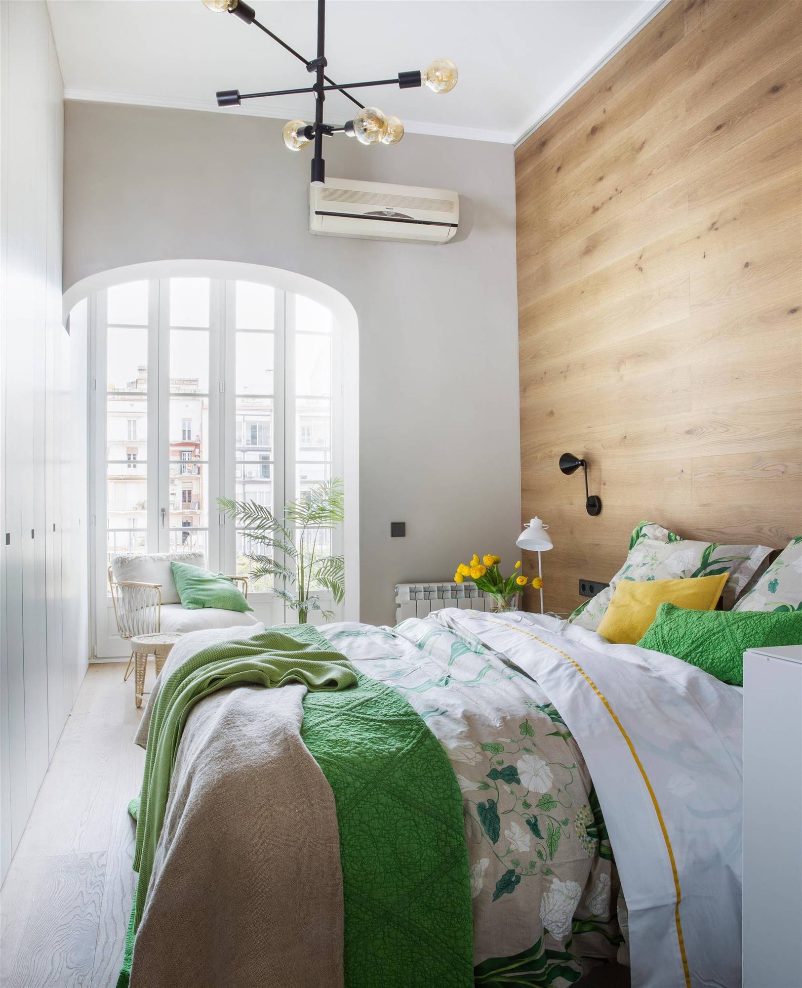 Dormitorio con la pared cabecero revestida de madera. 