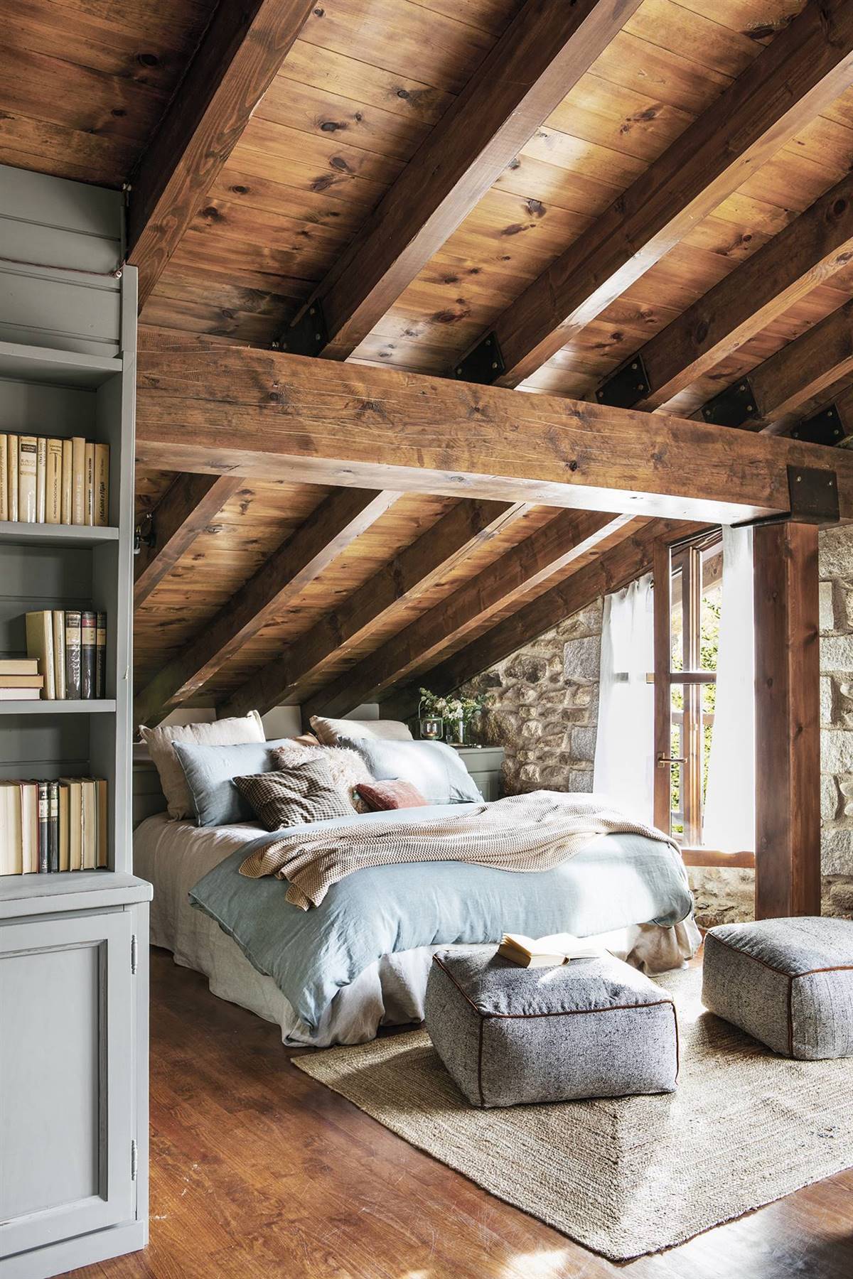 Dormitorio rústico abuhardillado con techos y paredes de madera. 