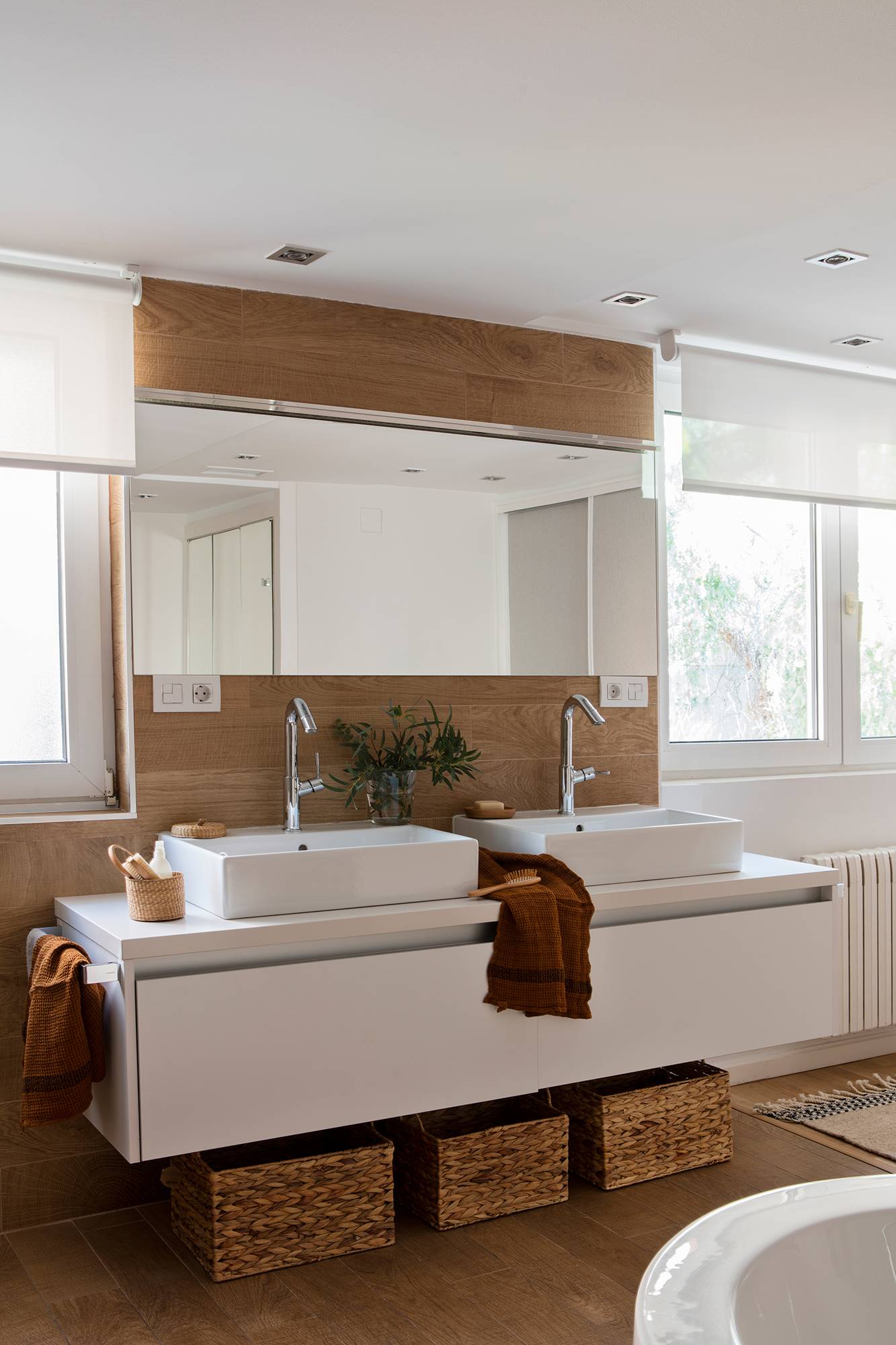Baño con ventanas vestidas con estor y mueble de baño moderno. 