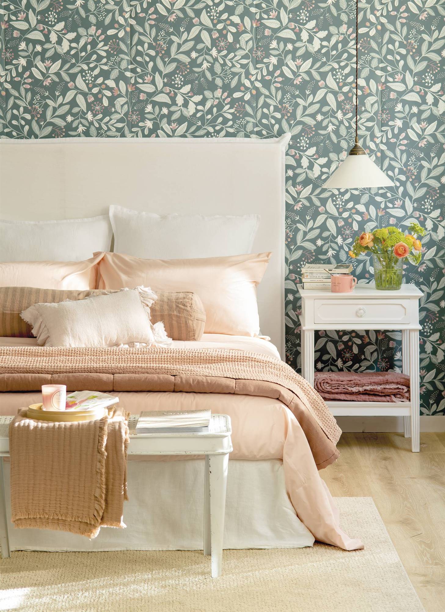 Dormitorio con cabecero de lino blanco y papel pintado con motivos botánicos.