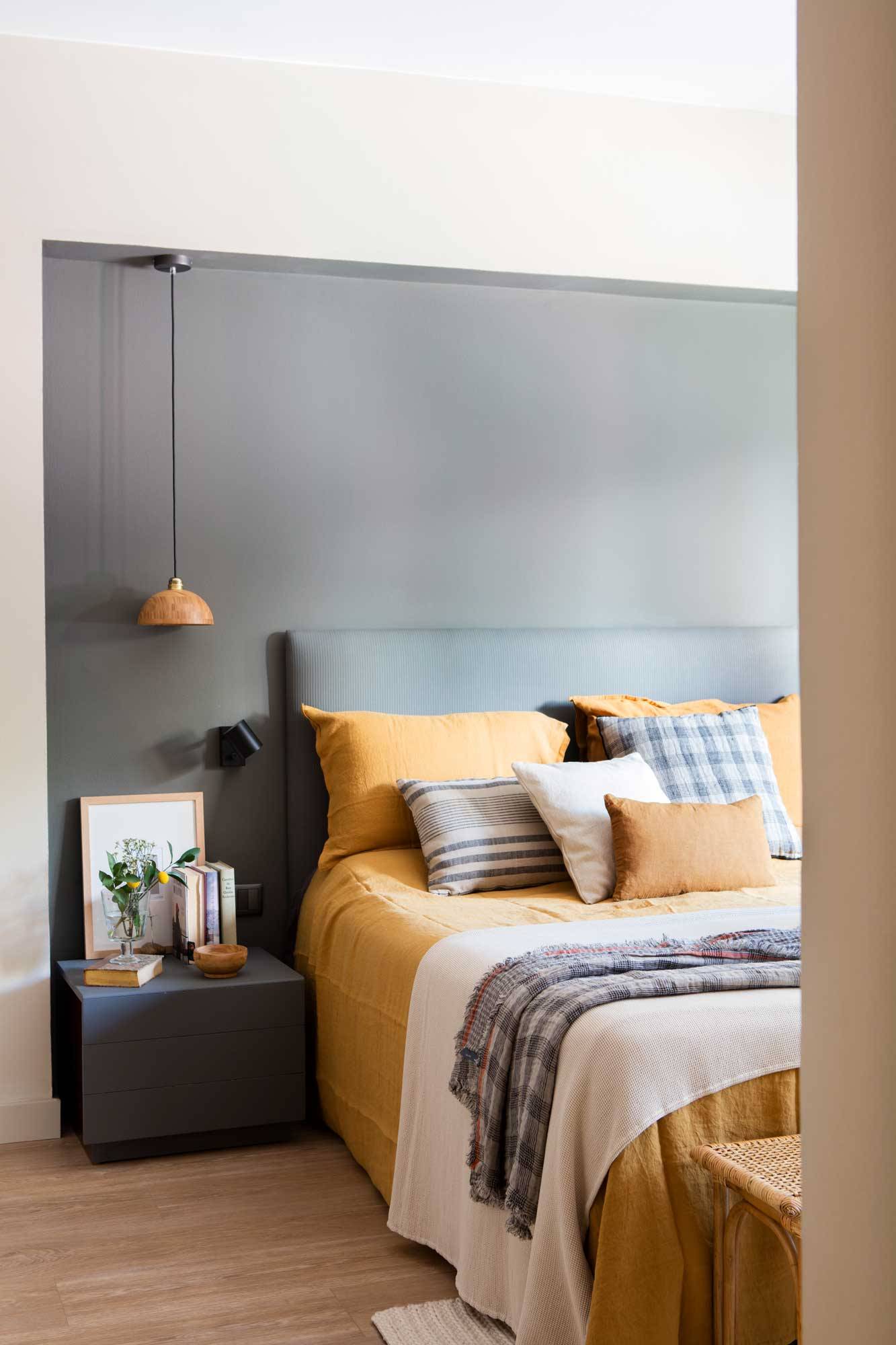 Dormitorio con la pared del cabecero pintada de gris. 