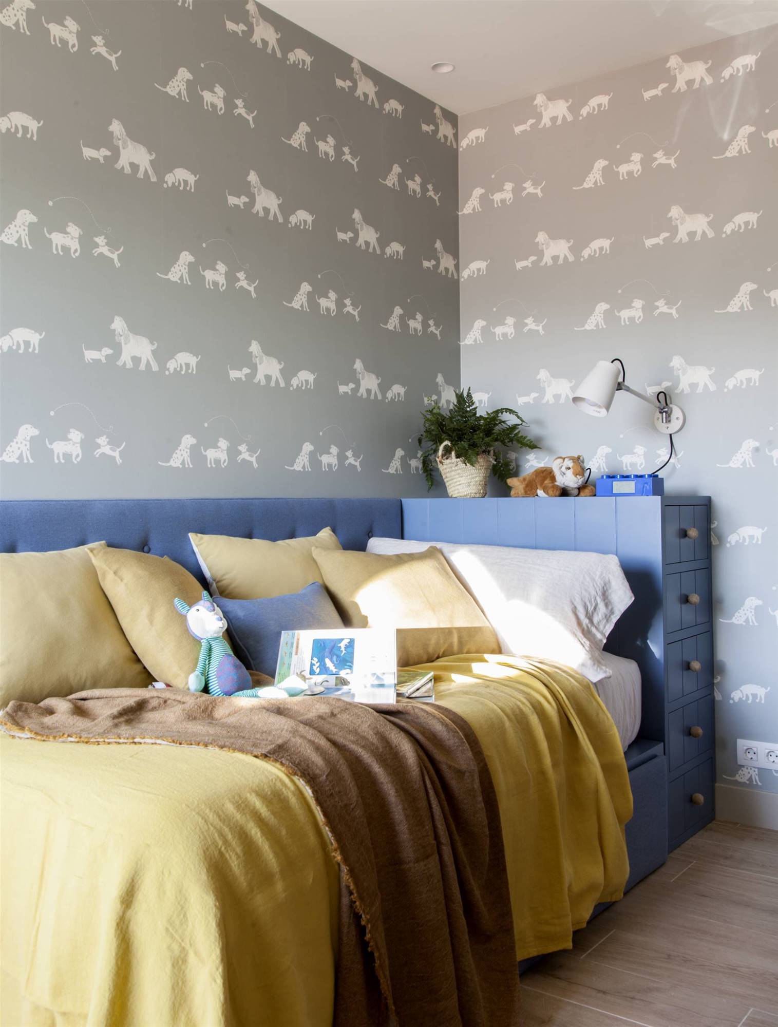 Dormitorio infantil con papel pintado de animales en gris y cama azul. 