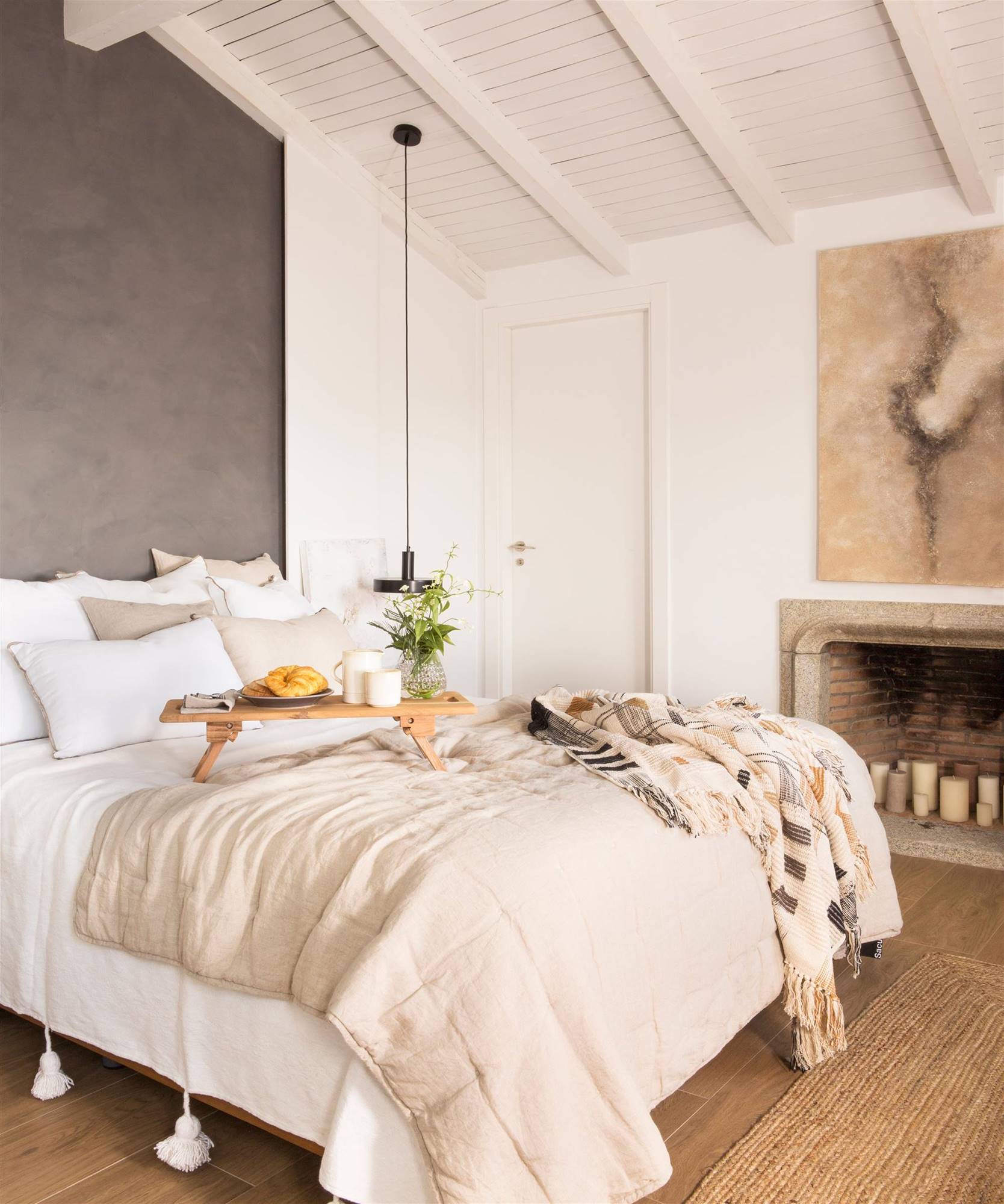 Dormitorio con chimenea y pared del cabecero pintada en gris intenso. 